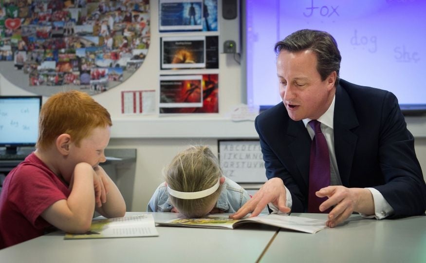 Prime Minister David Cameron helps with a reading lesson at the Sacred Heart Roman Catholic Primary School in Westhoughton near Bolton where he met pupils, Lucy Howarth , six, and Will Spibey, five, while on the General Election campaign trail. PA