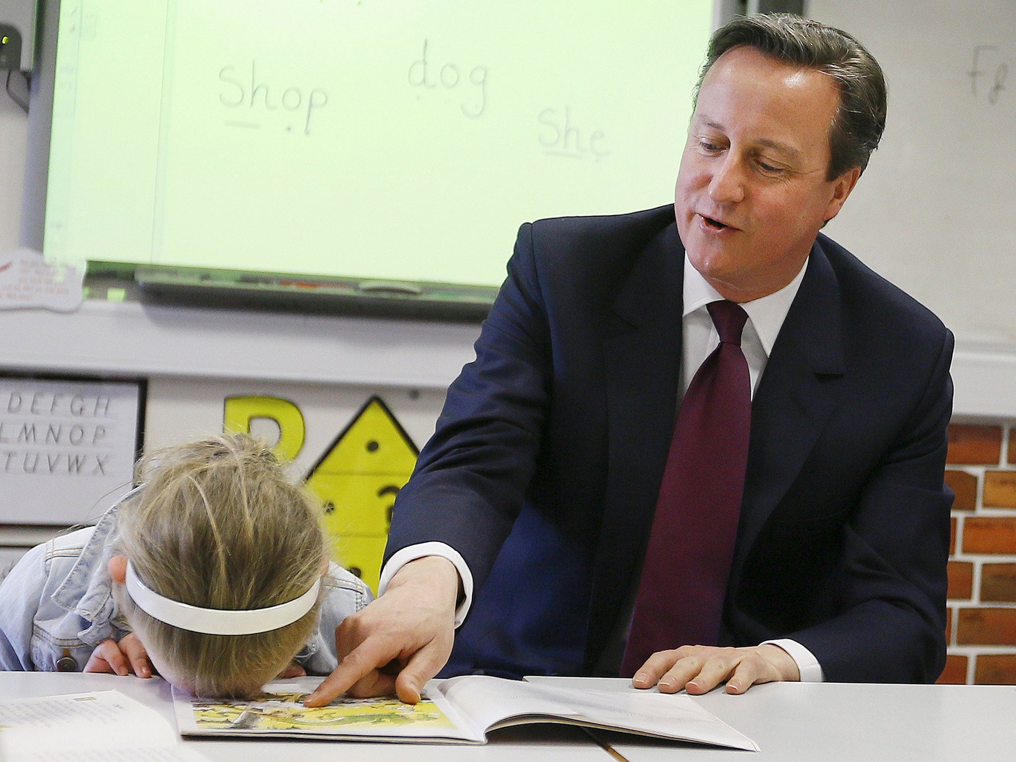 David Cameron reads a book to Lucy Howarth (6) during a visit to Sacred Heart RC primary school in Westhoughton near Bolton, northern England