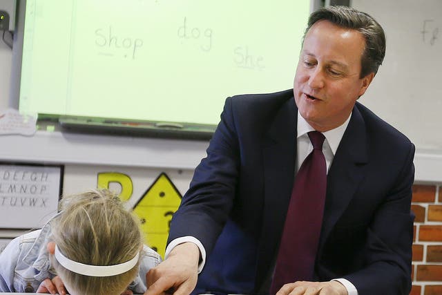 David Cameron reads a book to Lucy Howarth (6) during a visit to Sacred Heart RC primary school in Westhoughton near Bolton, northern England 