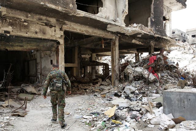 A Palestinian fighter walks through the rubble of the al-Yarmouk Palestinian refugee camp, south of Damascus, Syria