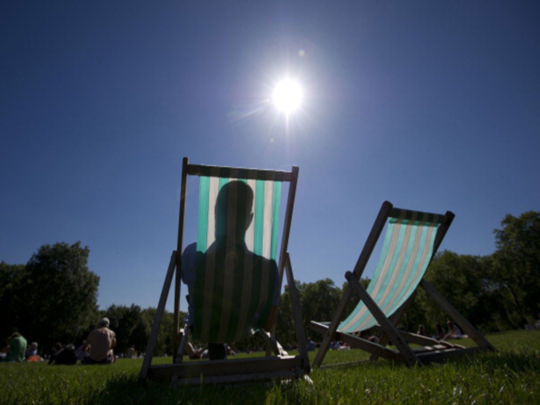 A man sits in a deckchair in a park in central London during hot weather