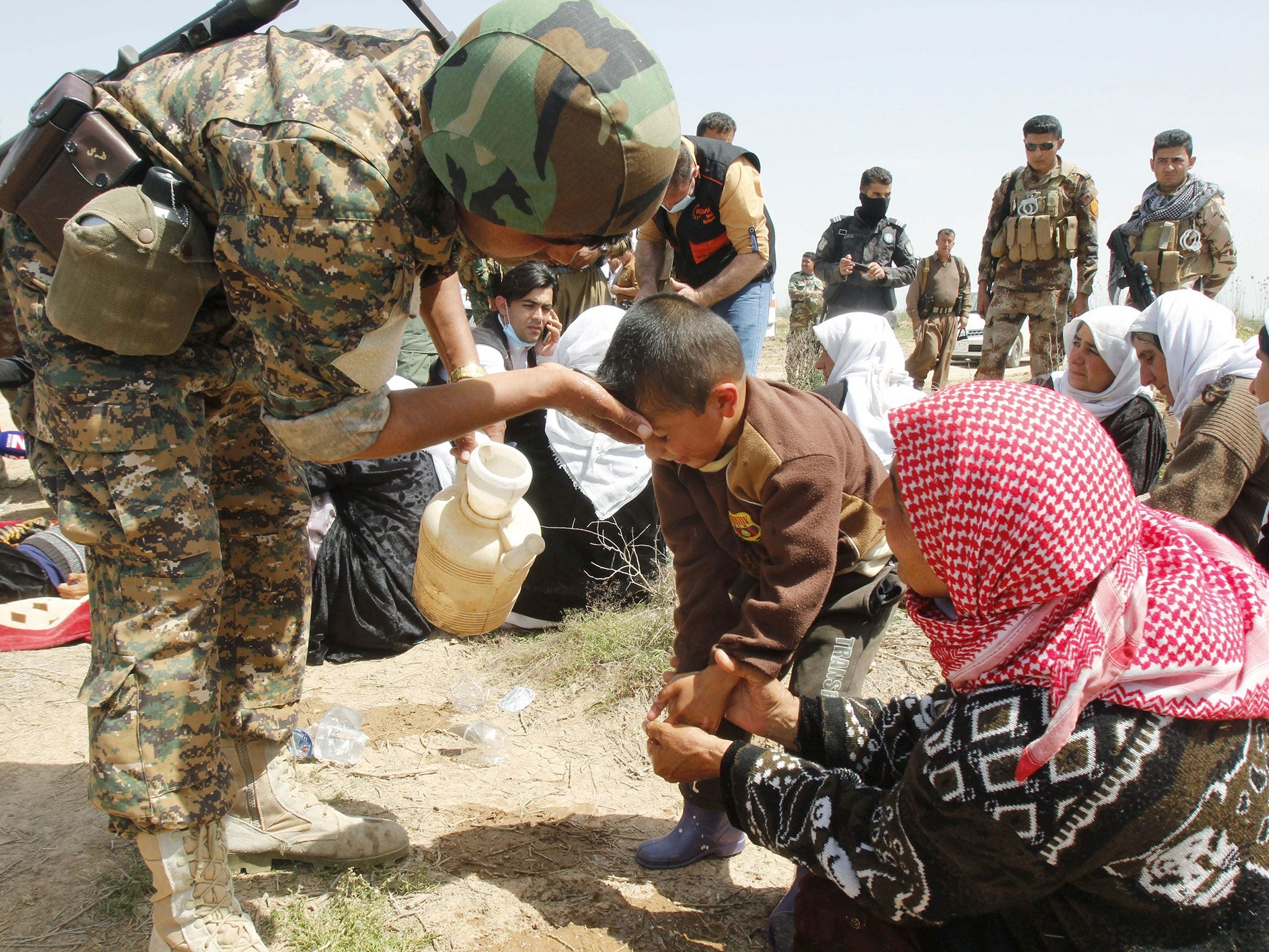 A member of the Kurdish Peshmerga forces helps people from the minority Yazidi sect after more than 200 were freed by Isis