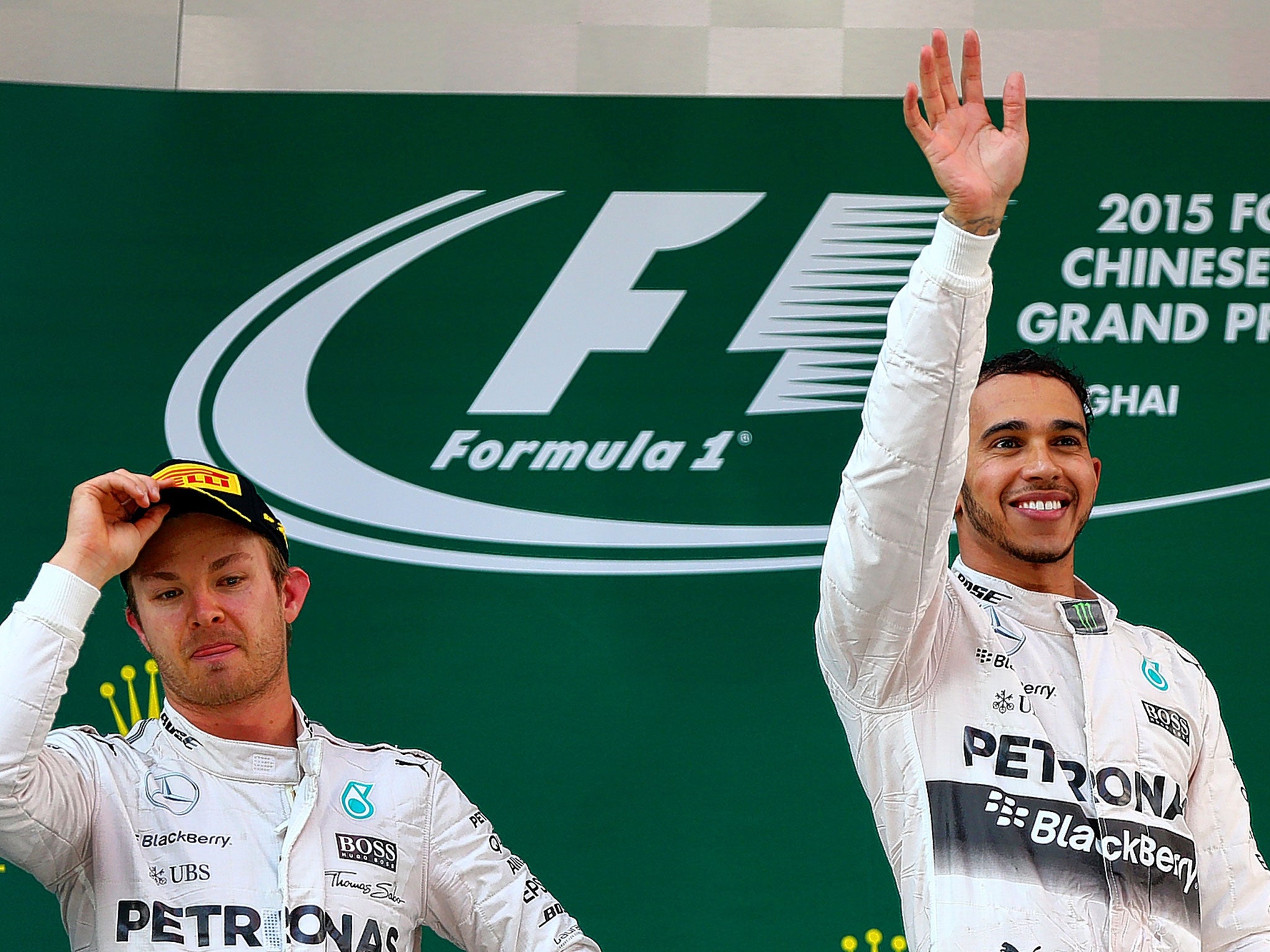 Nico Rosberg (left) looks none too impressed as his team-mate Lewis Hamilton celebrates victory in Shanghai