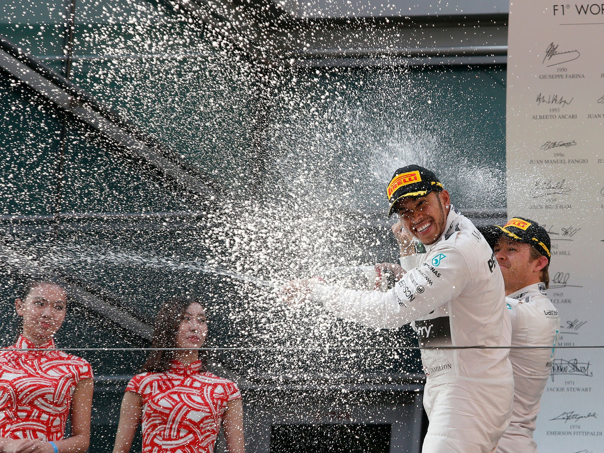 Mercedes driver Lewis Hamilton of Britain is celebrated with champagne by teammate Nico Rosberg, right, of Germany on the podium after winning the Chinese Formula One Grand Prix at Shanghai International Circuit in Shanghai, China