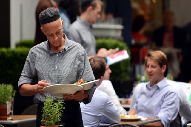 A waitress clears a table at a restaurant in central London