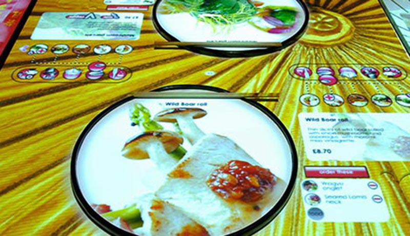 E-table menus are displayed on the tables using a combination of ceiling projectors and a table interface.