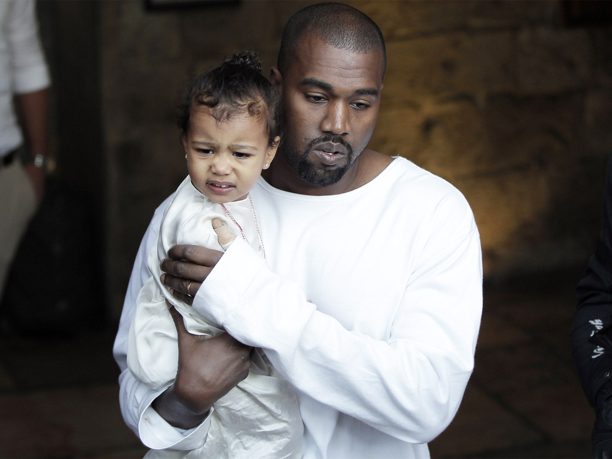 Rapper Kanye West carries daughter North following the baptism ceremony