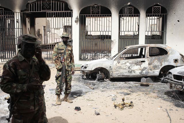 Nigerian soldiers stand guard in front of the burned out palace of the Emir of Gwoza, in Gwoza, Nigeria, a town newly liberated from Boko Haram