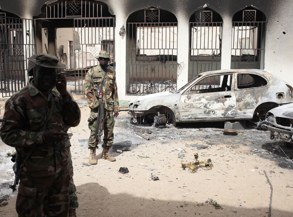 Nigerian soldiers stand guard in front of the burned out palace of the Emir of Gwoza, in Gwoza, Nigeria, a town newly liberated from Boko Haram