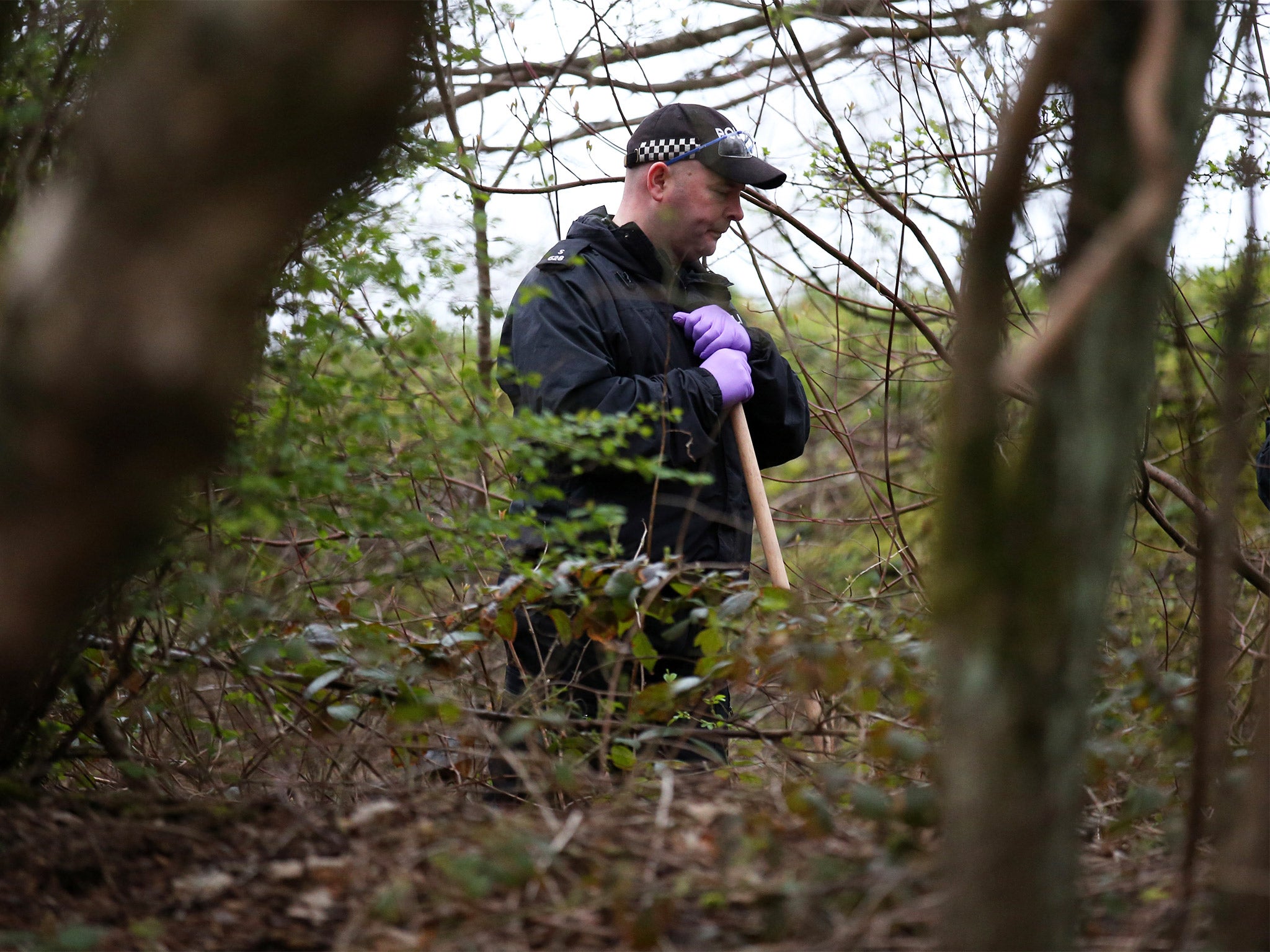 A police officer searches the undergrowth in Dawsholm Park in Glasgow