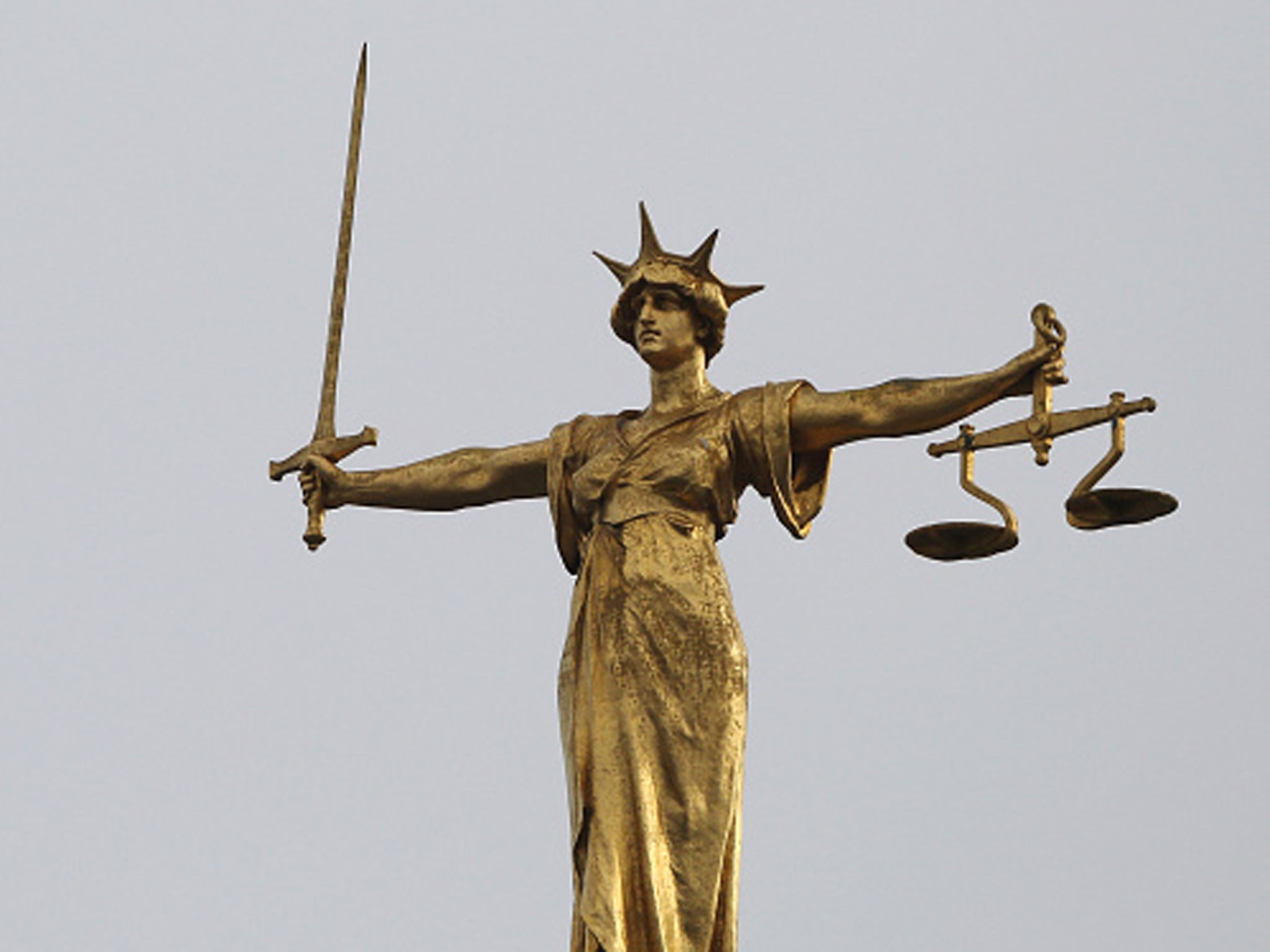 A statue of the scales of justice stands above the Old Bailey