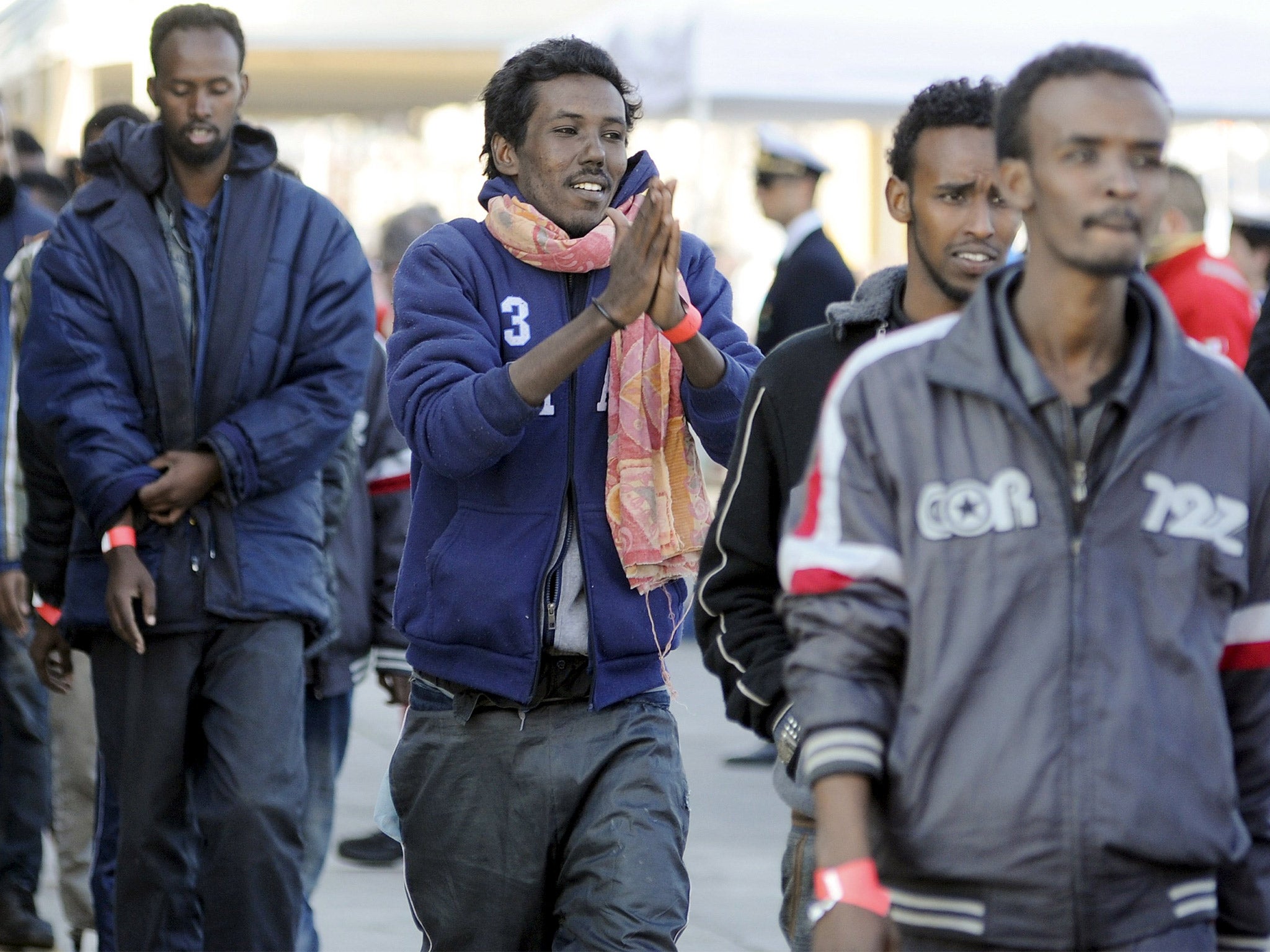 Migrants disembark from a merchant ship as they arrive in the Sicilian harbour of Palermo on Wednesday