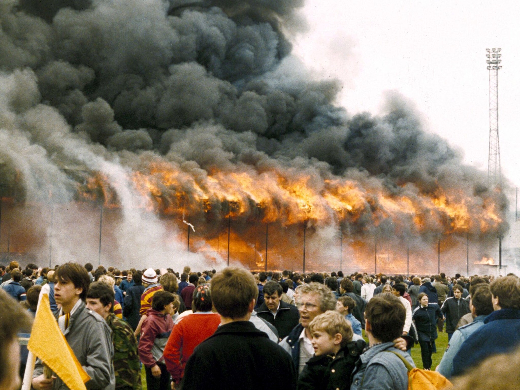 Crowds on the pitch at Valley Parade stadium after the stand caught fire on 11 May 1985. The disaster killed 56 supporters