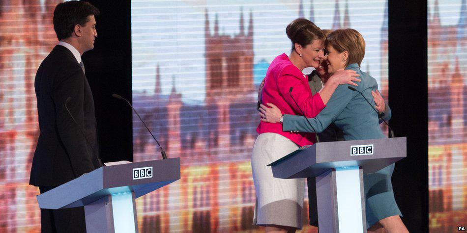 Ed Miliband looks on as the three women in the debate embrace