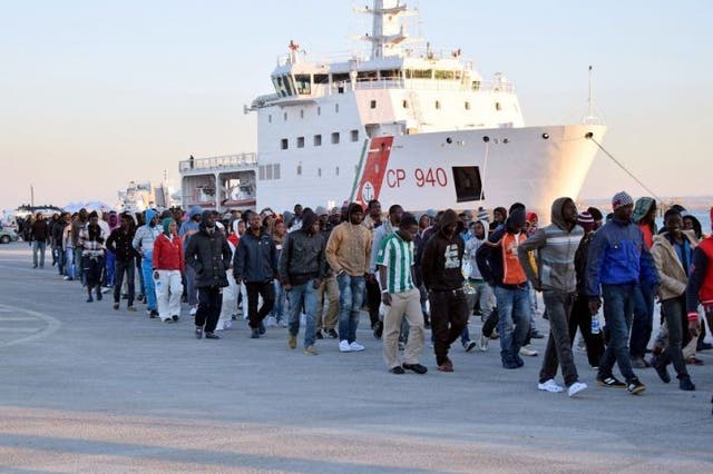 Shipwrecked refugees disembark from a rescue vessel as they arrive in Augusta, Italy