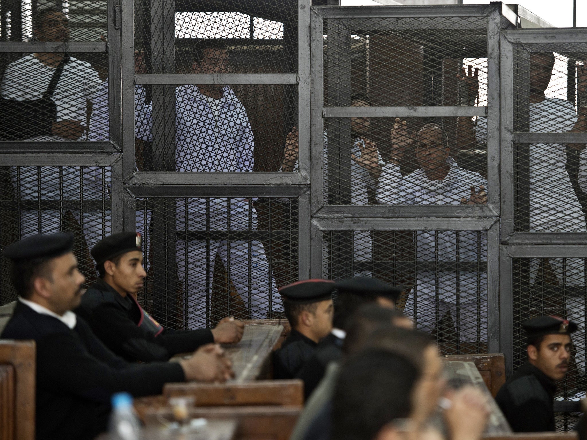 Al-Jazeera journalist Peter Greste and his colleagues stand in the defendants' cage at their trial in Cairo for allegedly support the Muslim Brotherhood