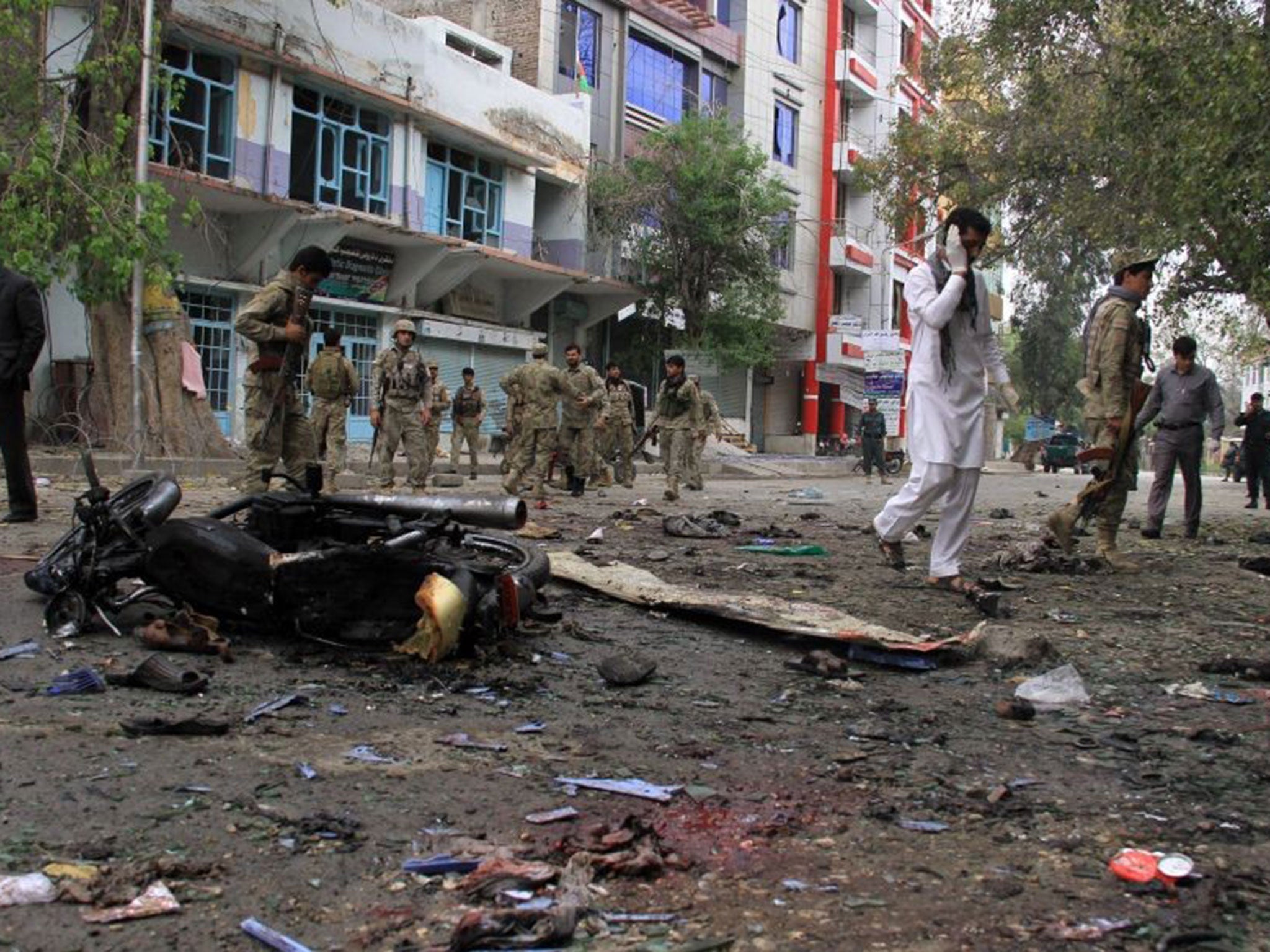 Police inspect the scene of the suicide bombing in Jalalabad on 18 April
