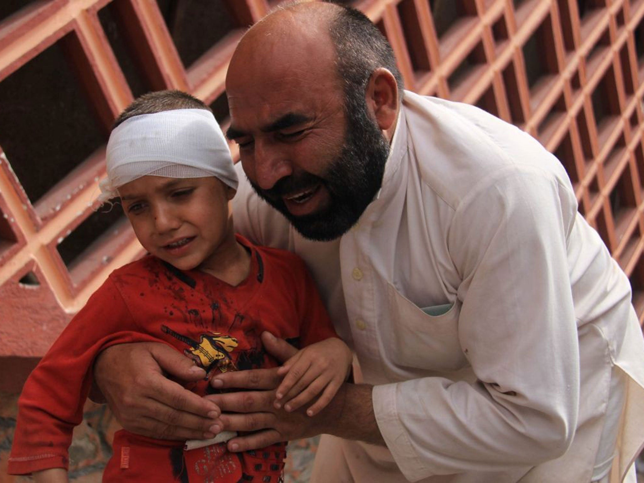 An Afghan man holds his son who was injured in a suicide bomb attack in Jalalabad