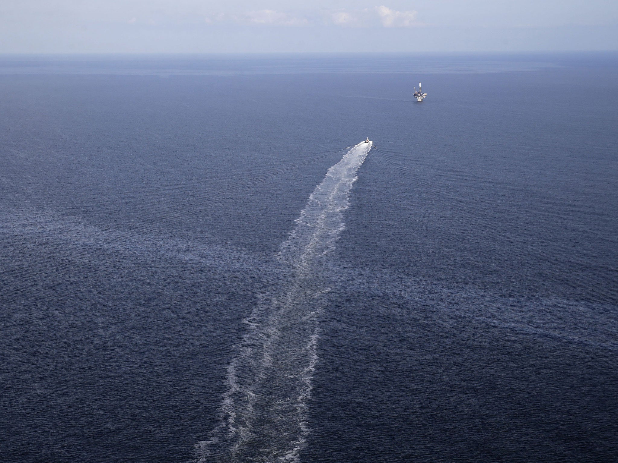 In this March 31, 2015 photo, the wake of a supply vessel heading towards a working platform crosses over an oil sheen drifting from the site of the former Taylor Energy oil rig in the Gulf of Mexico, off the coast of Louisiana