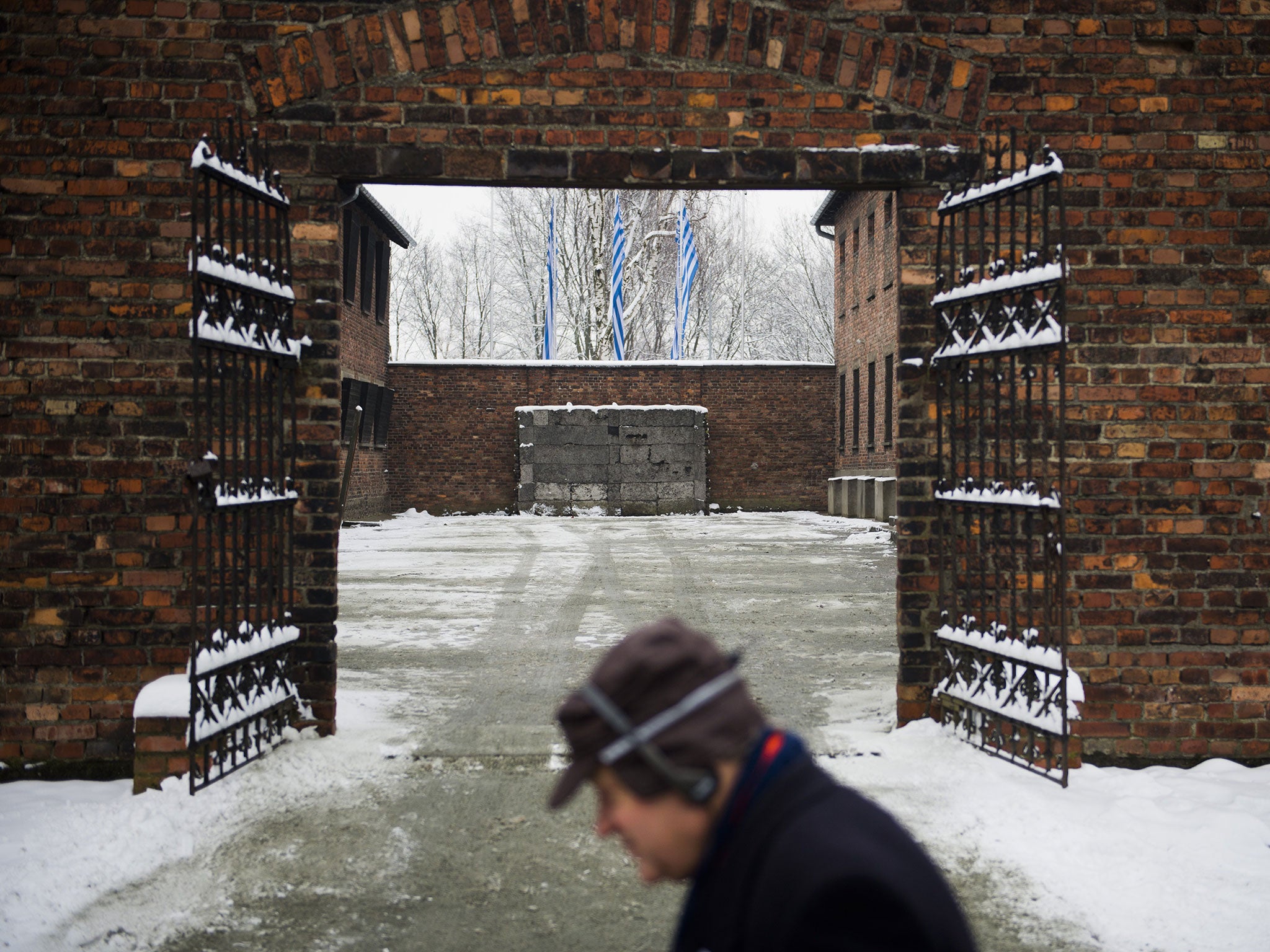 A visitor walks past the gates with the 'death wall' behind it in the former Auschwitz concentration camp held by the Nazis in Oswiecim