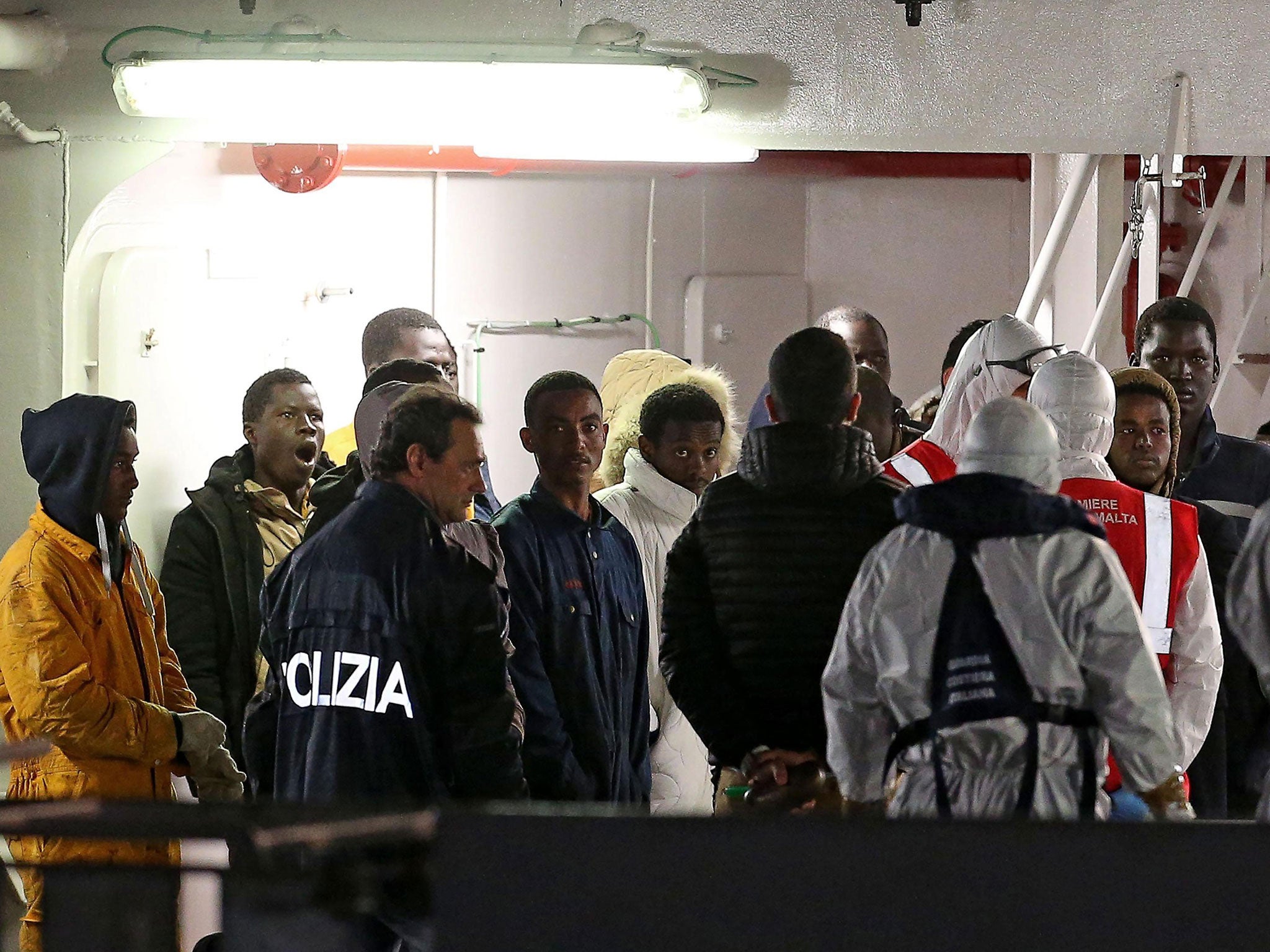 Italian authorities guide migrants who survived recent ship sinkings upon arrival onboard the Italian Coast Guard's vessel Bruno Gregoretti at Catania's port, Sicily, Italy, early 21 April 2015