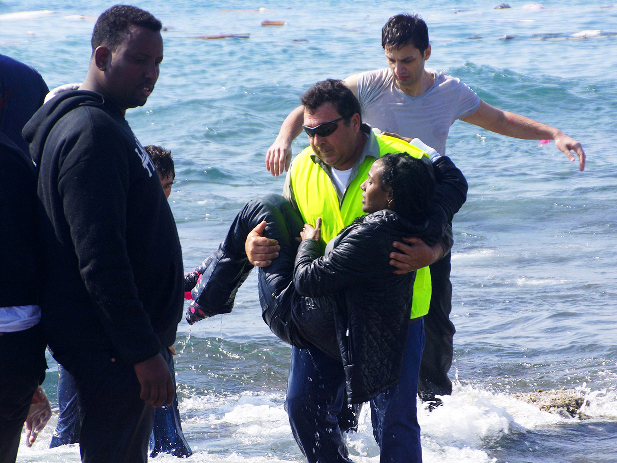 A man rescues a migrant from the Aegean sea, in the eastern island of Rhodes, in late April