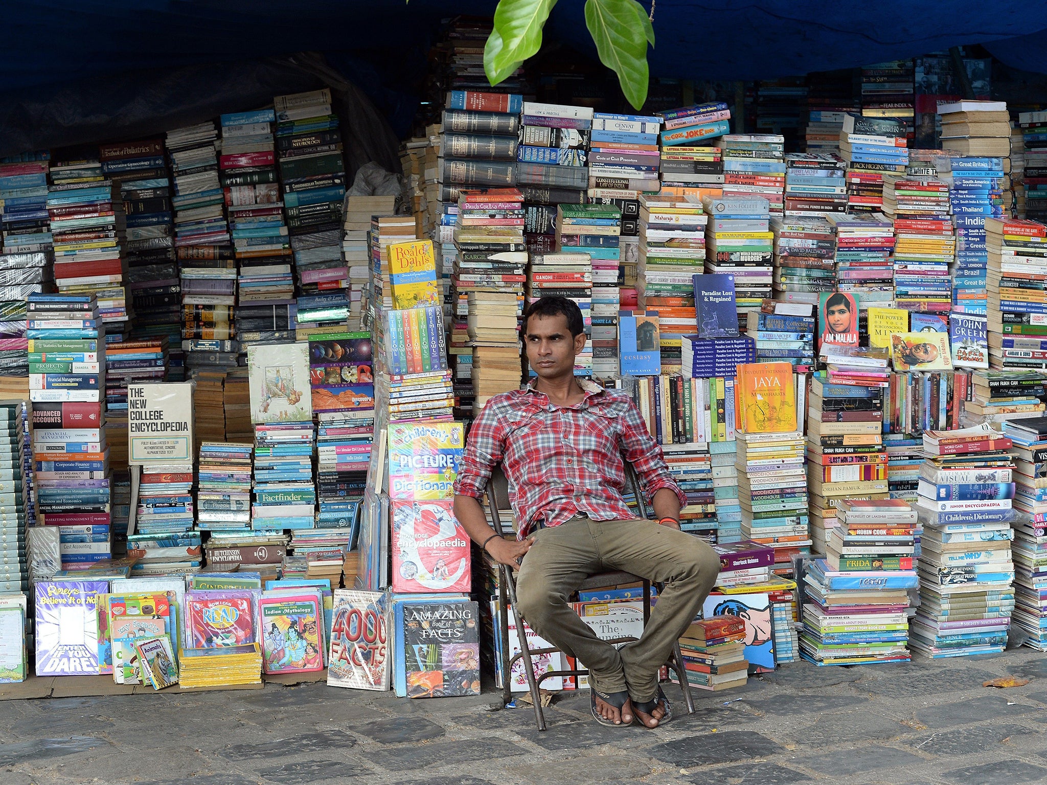 An Indian bookseller waits for customers at a roadside stall on World Book and Copyright Day in Mumbai