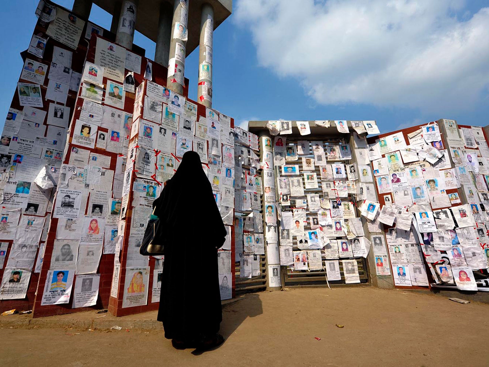 A women looks at the photos of missing Rana Plaza victims pasted up on the wall of Adhar Chandra High School in Savar © Khorshed Alam Rinku