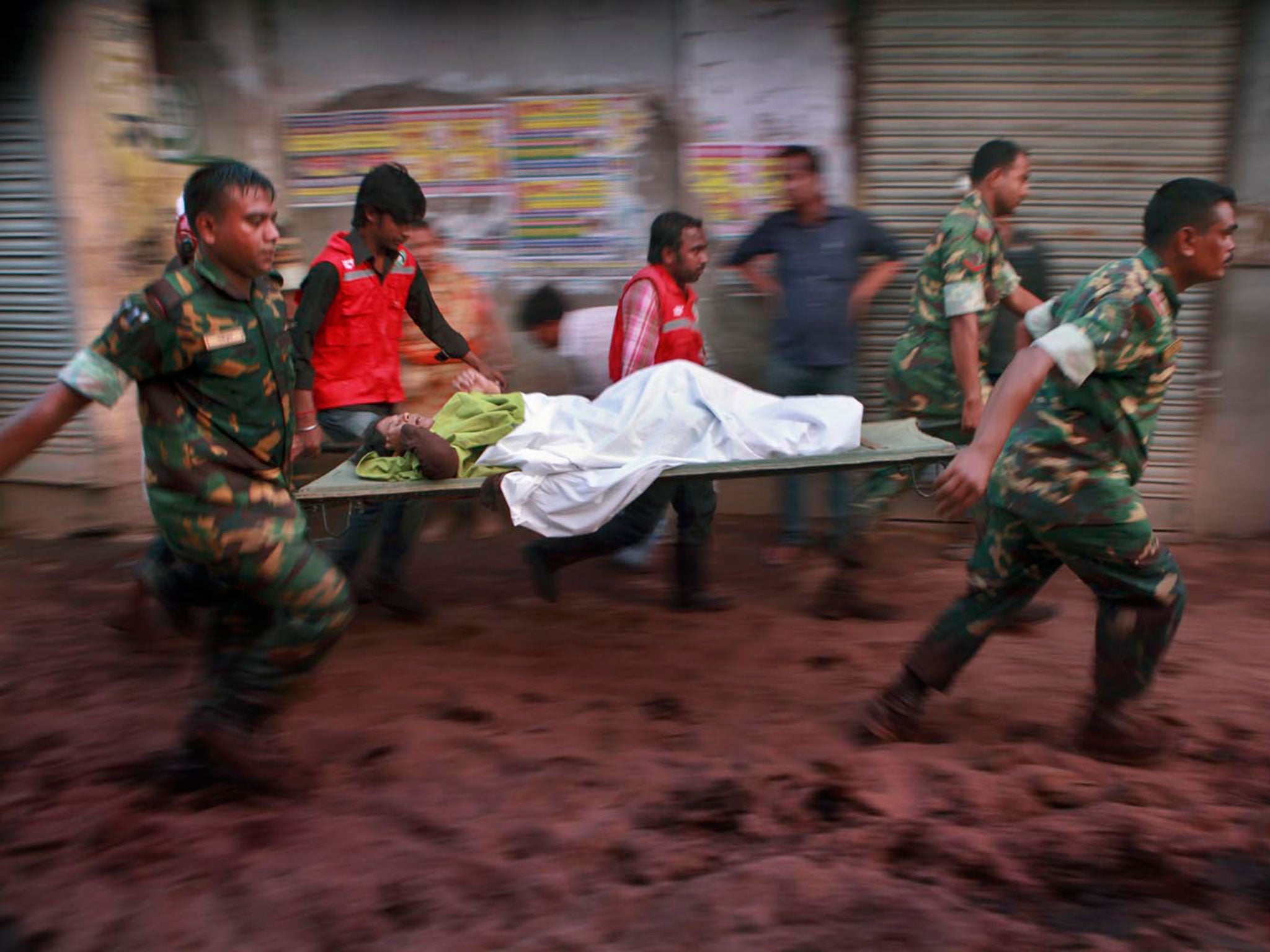 Rescuers from Bangladesh Army with the help of volunteers carry an injured worker to an ambulance to shift her to a hospital © Abdullah Apu