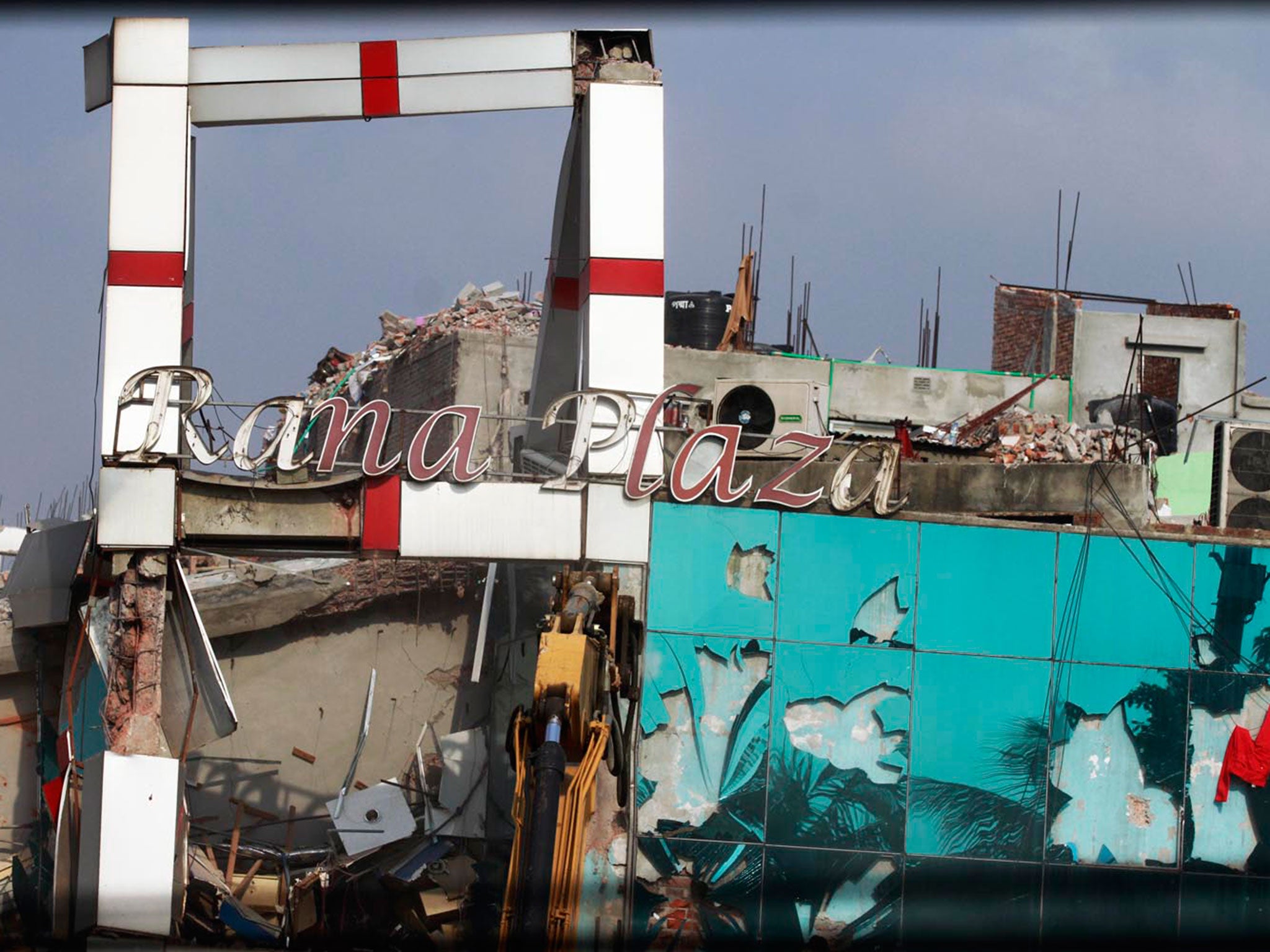 A signboard outside the factory reads “Rana Plaza” as it collapses on 24 April 2013
