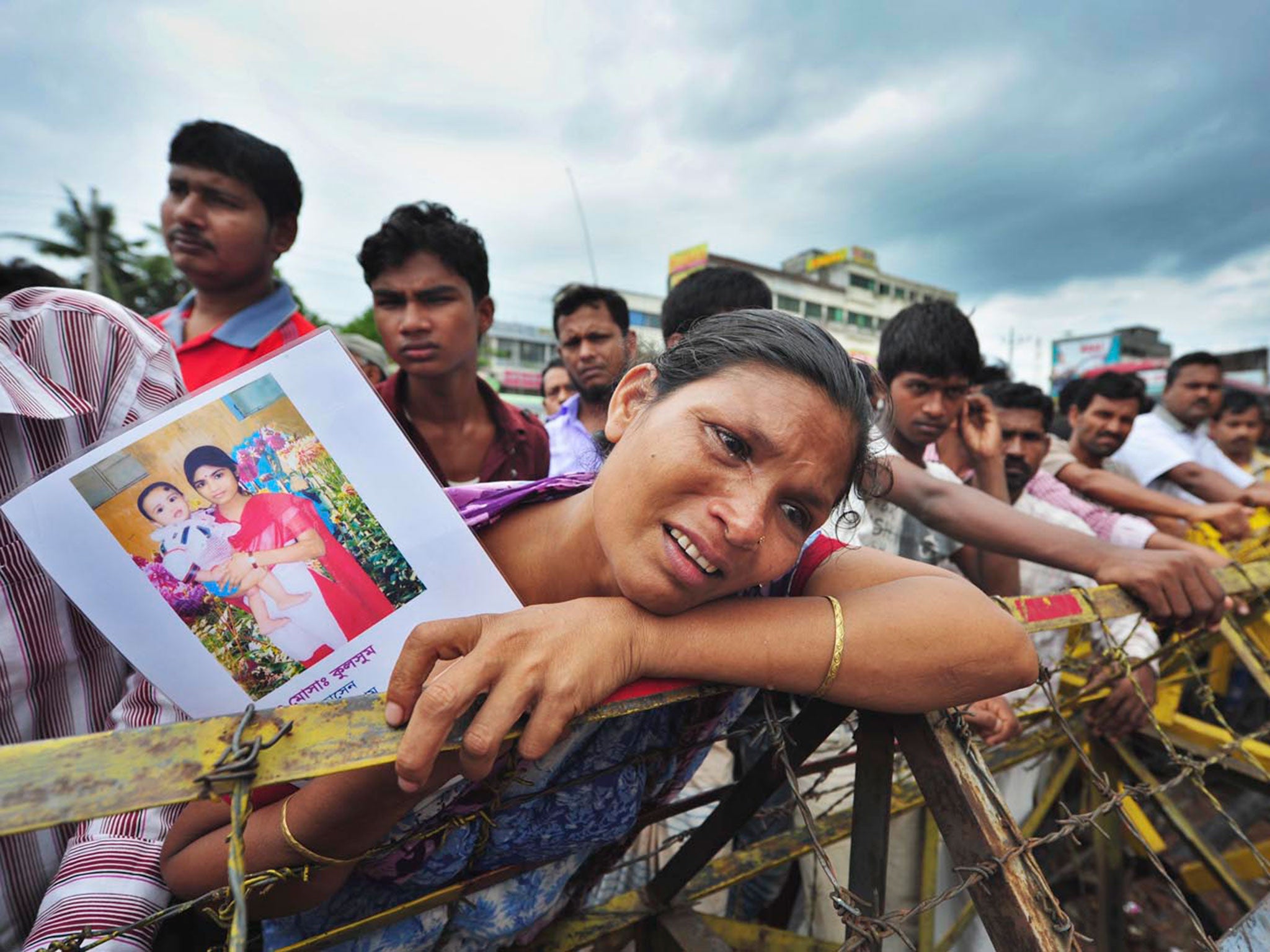 Protesters at the Rana Plaza site hold up pictures of victims of the disaster © Khorshed Alam Rinku