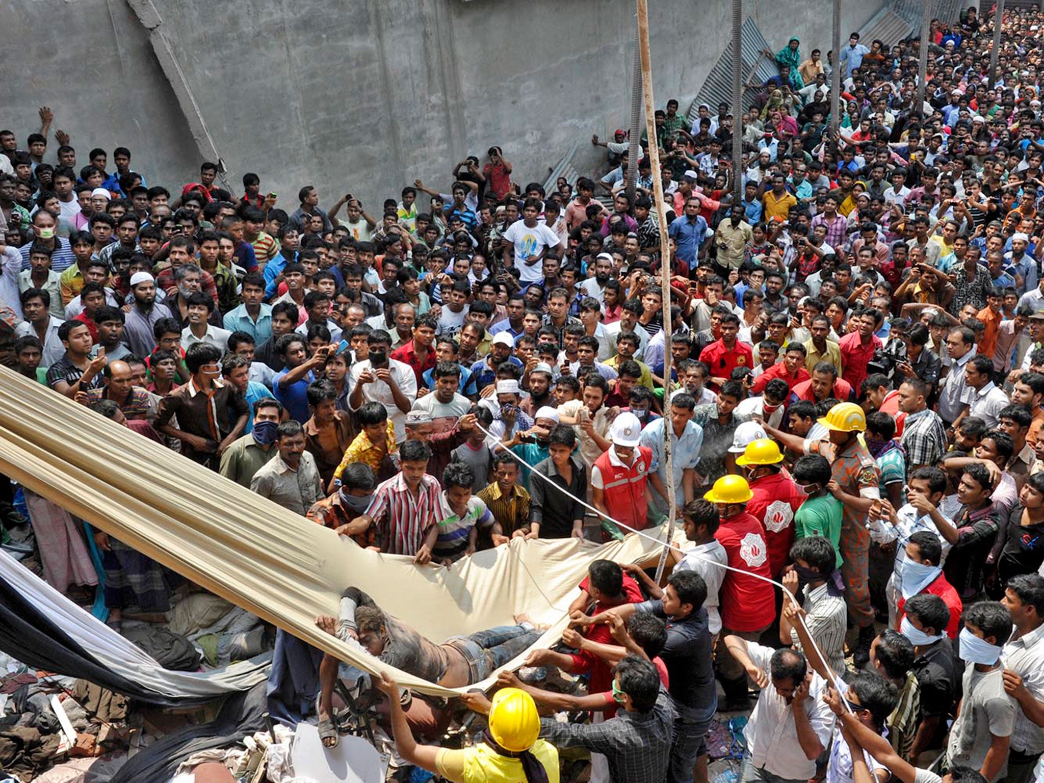 Hundreds of onlookers gather and stand watching the rescue operation as rescuers pull out bodies and wounded workers of the collapsed factory building in Savar, Dhaka © Nazrul Islam Khan