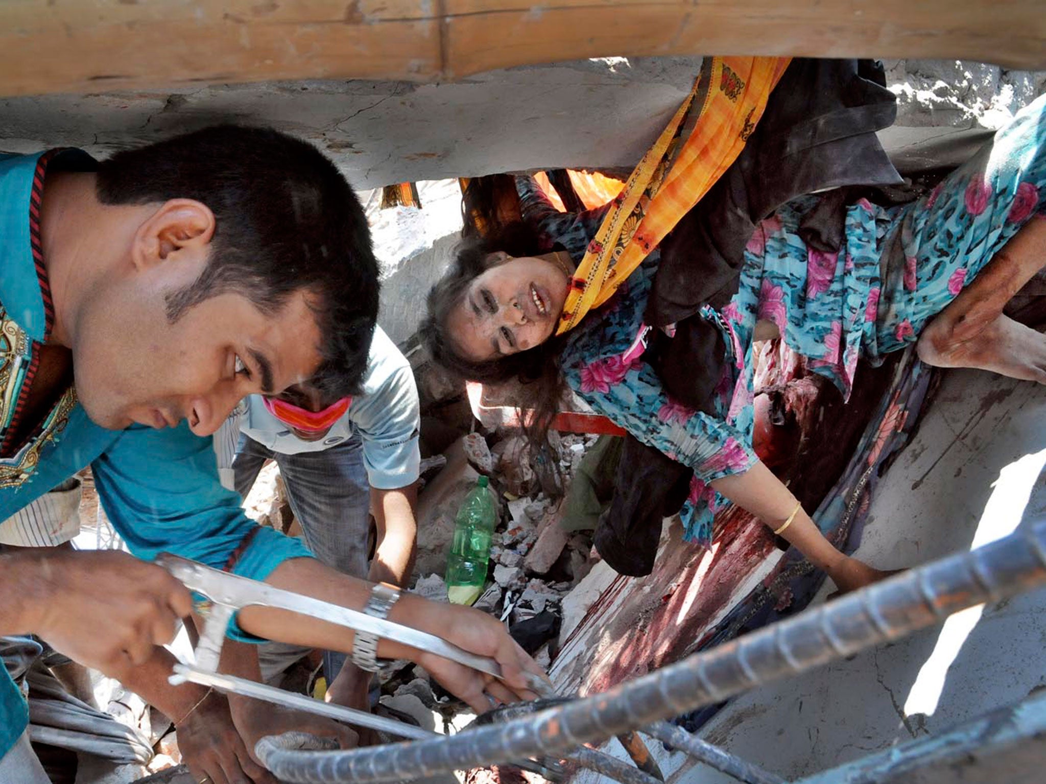 A voluntary rescuer cuts iron rods with a hacksaw to rescue a worker trapped beneath debris of collapsed Rana Plaza building in Savar on the outskirts of Dhaka in April 2013 © Sanaul Haq