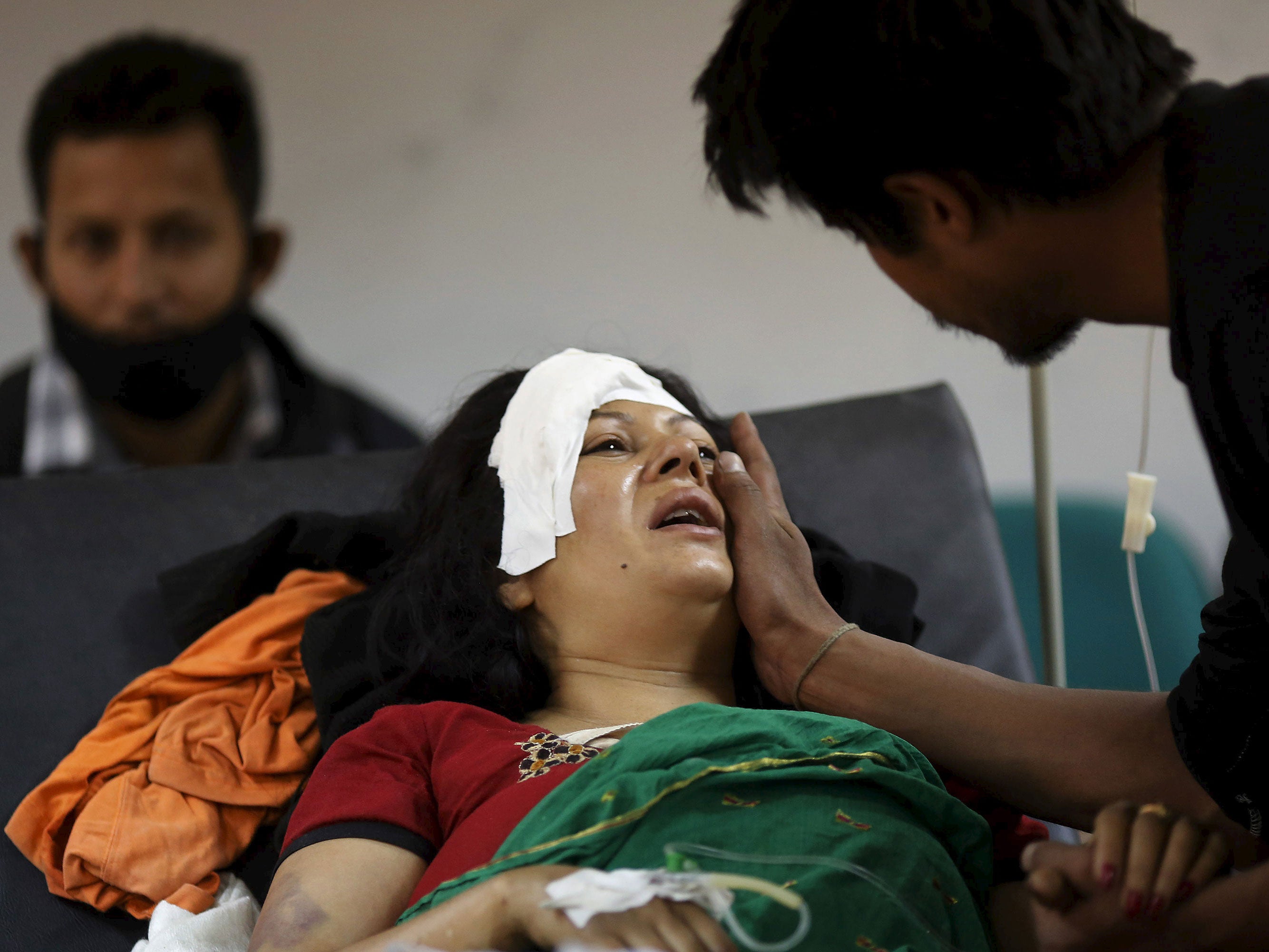 A boy comforts his mother who was injured during an earthquake, at a trauma center in Kathmandu, Nepal