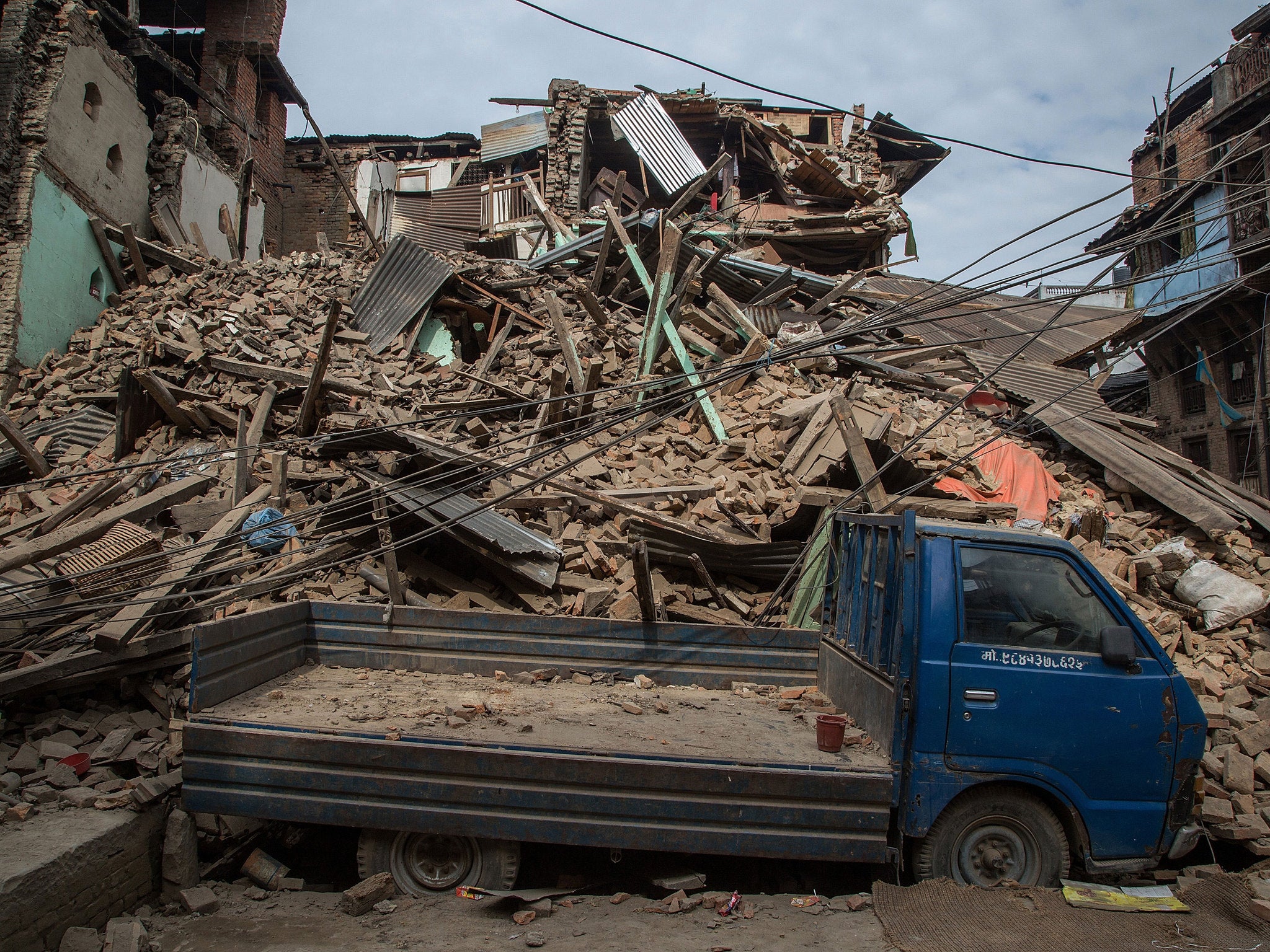 A truck is covered in debris from a collapsed building