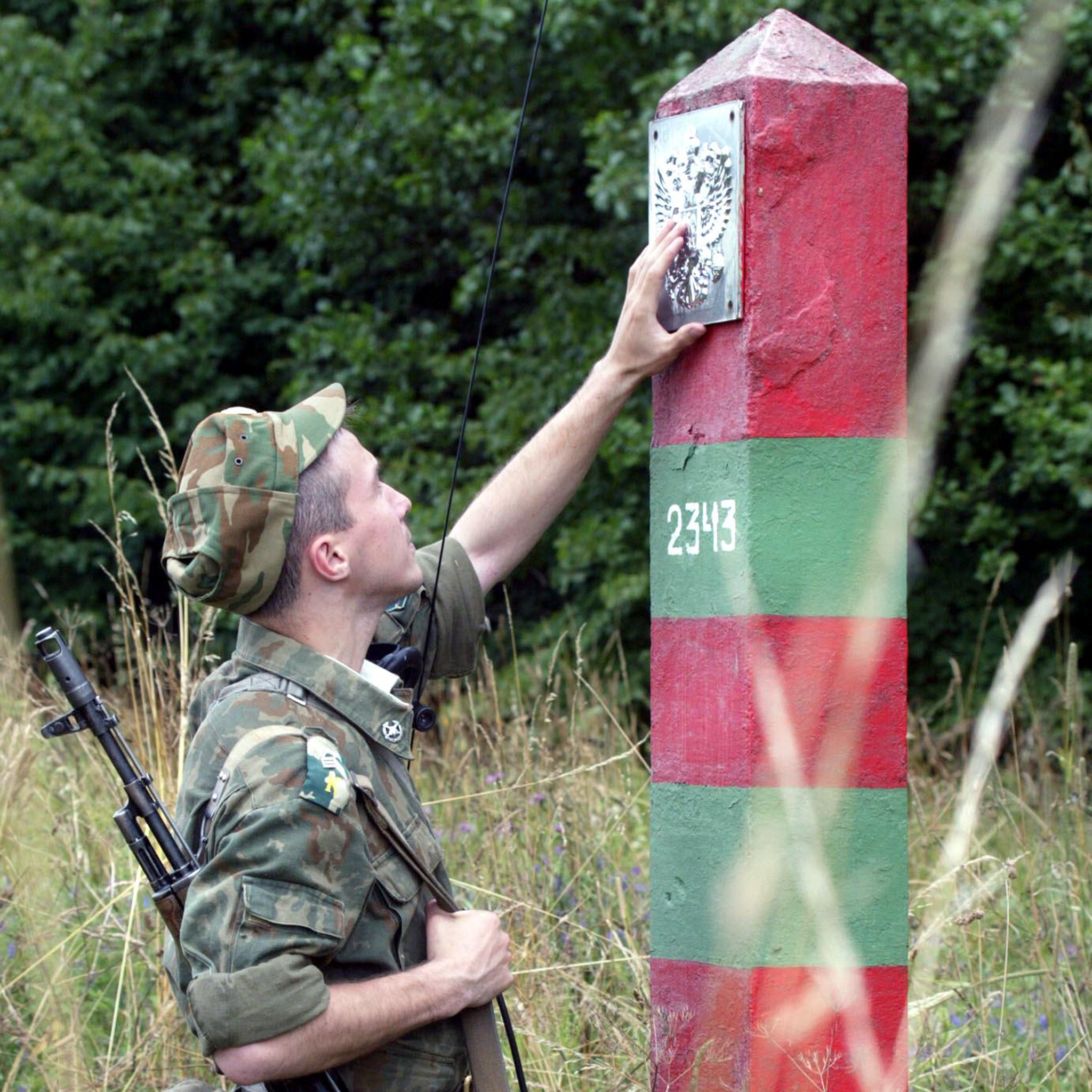 A Russian frontier guard soldier inspects Russian border sign on Russian-Polish border near the village of Bagatovo in Kaliningrad region
