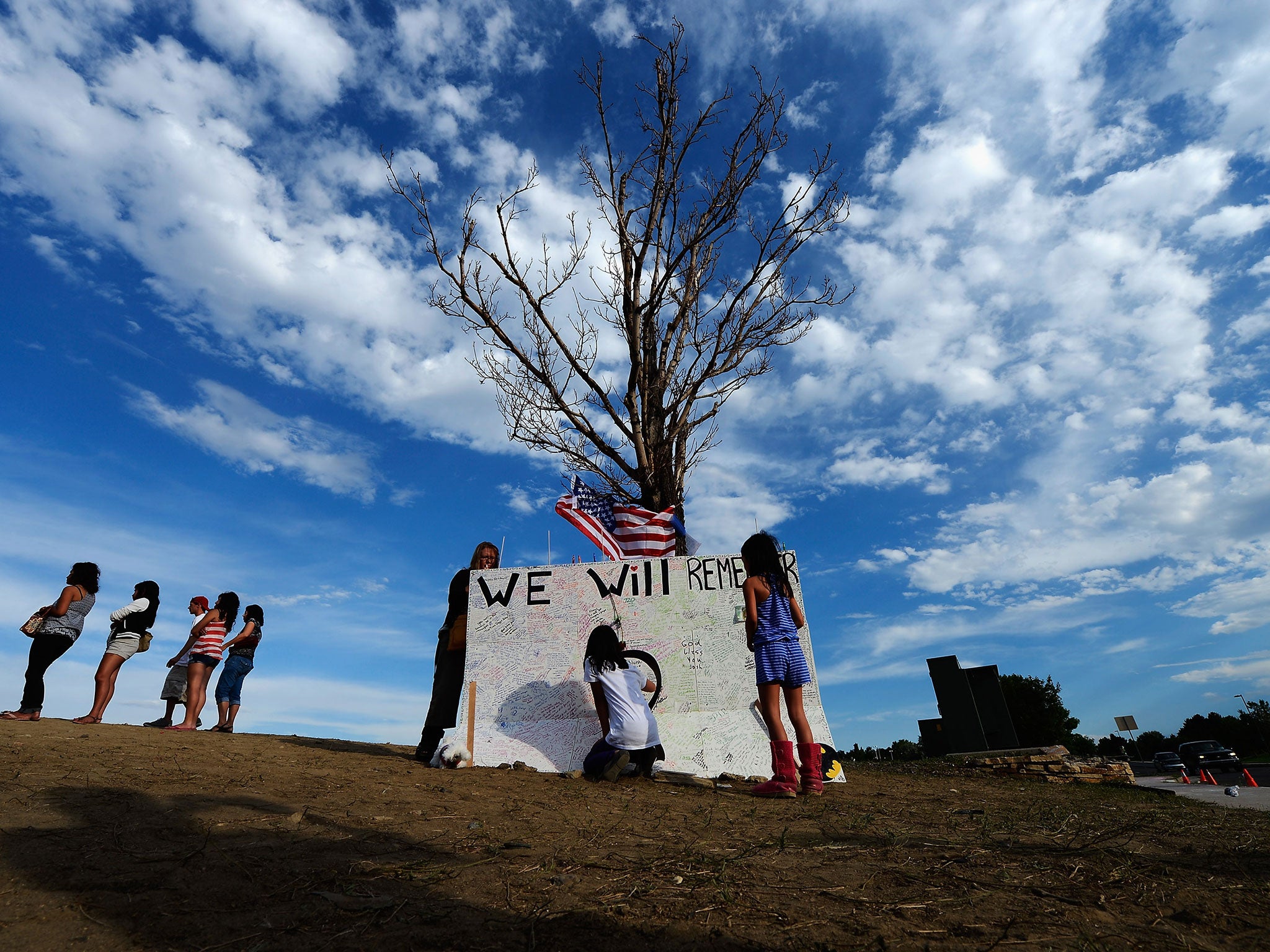 Children sign a message board at the makeshift memorial across the street from the cinema in Aurora, Colorado, where the 12 victims died
