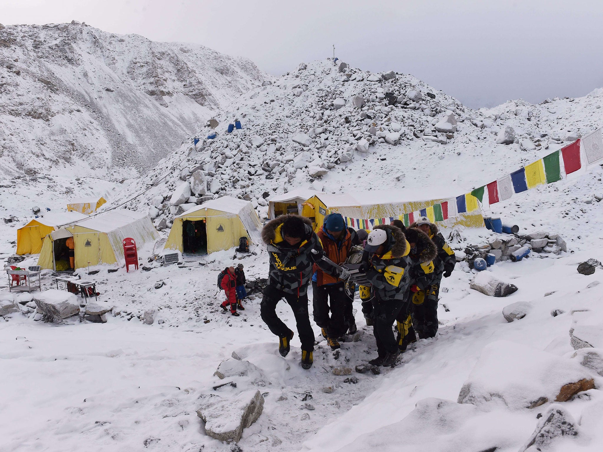 An injured person is carried to a helicopter to be airlifted out of Everest Base Camp, where 17 climbers were killed in avalanches triggered by the quake