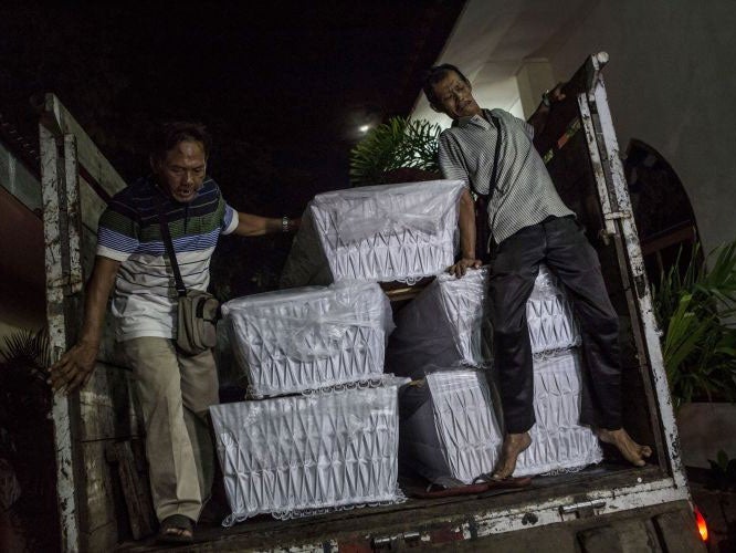 Workers load coffins into a lorry ahead of the execution of nine prisoners in Indonesia