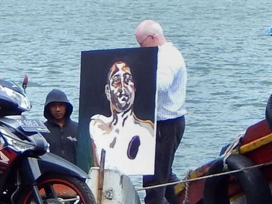The lawyer for Australian death row inmates Myuran Sukumaran carries a painting after visiting Indonesia's Nusakambangan Island