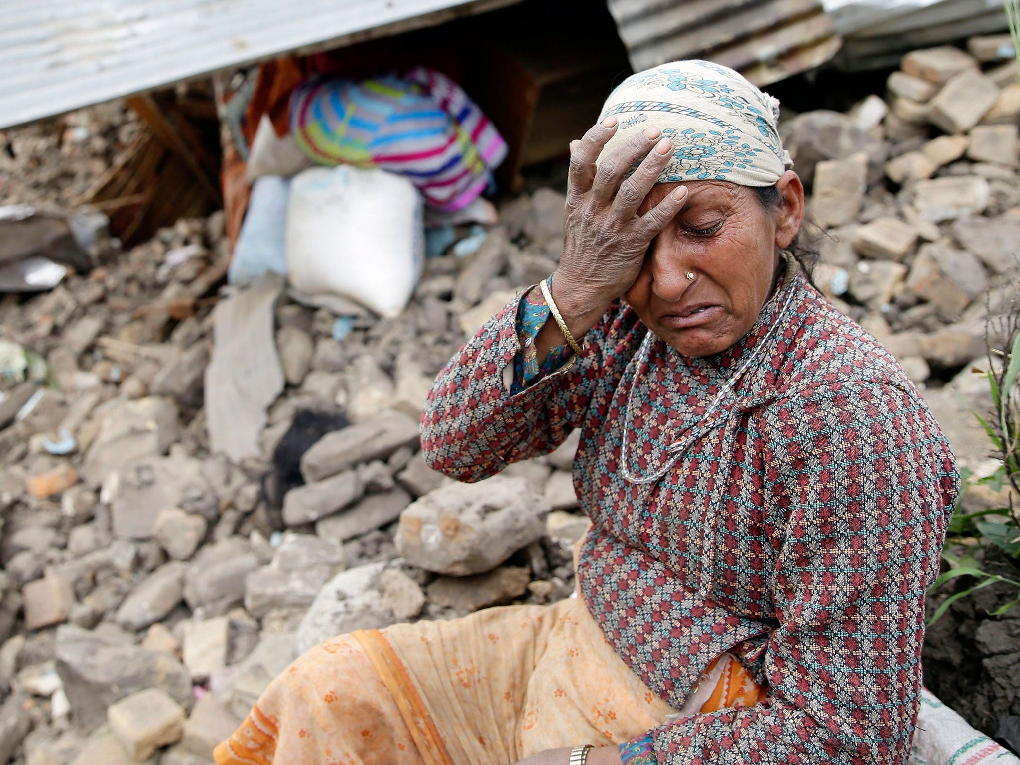 An elderly woman mourns in front of her destroyed home in the Kumalpur village, on the outskirts of capital Kathmandu