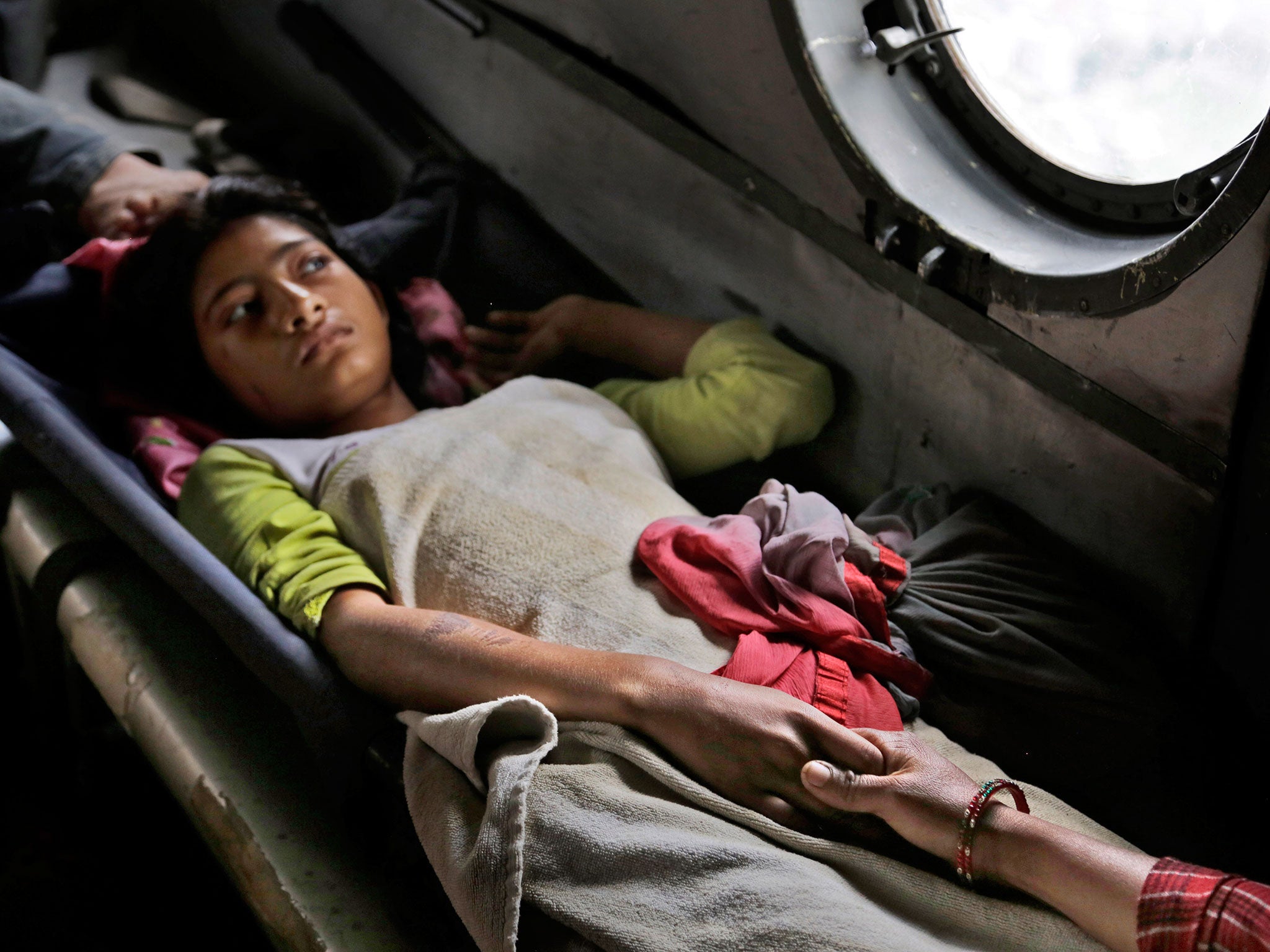 A Nepalese girl injured in the earthquake holds the hand of her mother inside an Indian air force helicopter