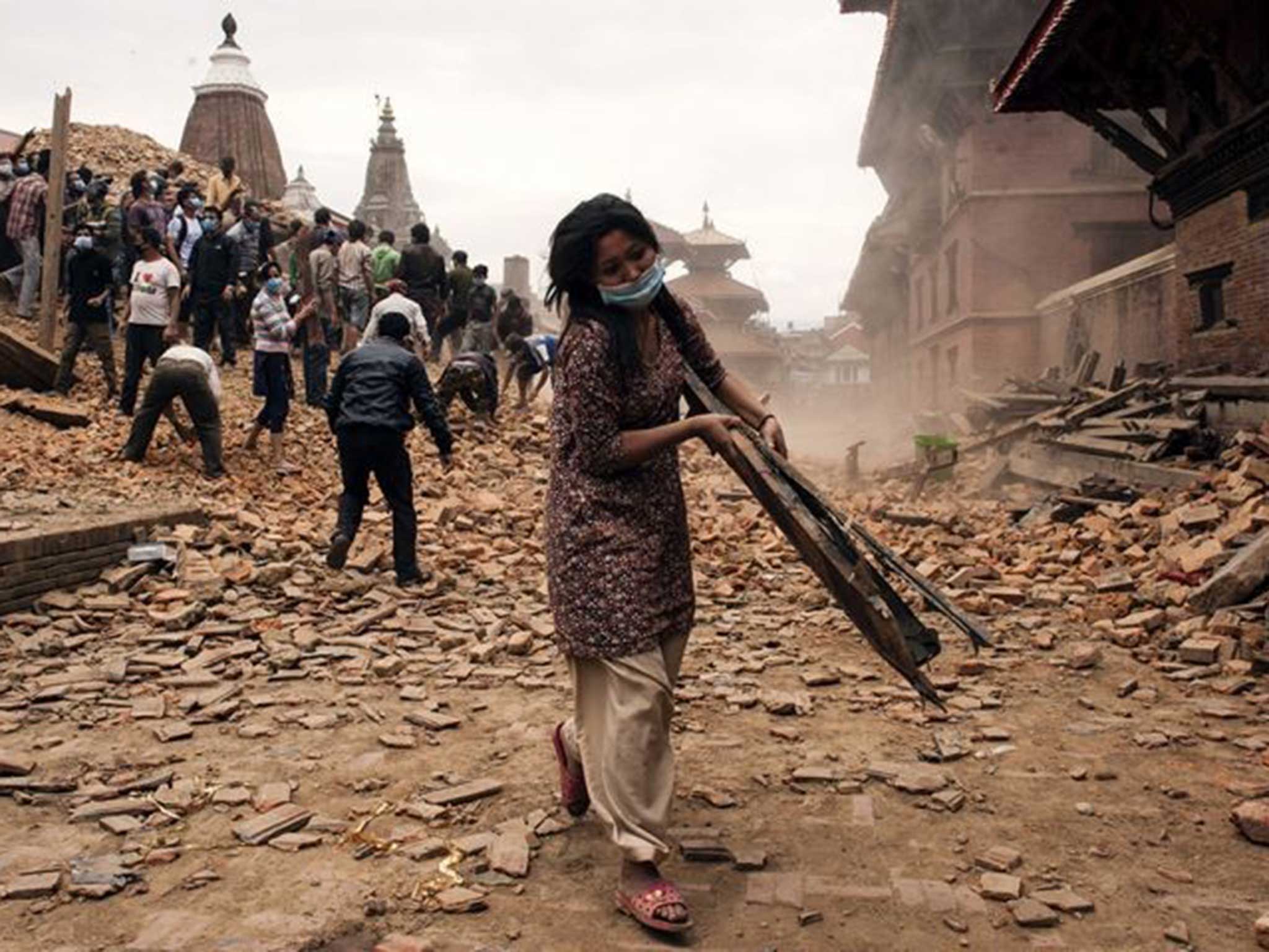 A woman helps pick through the rubble in Kathmandu