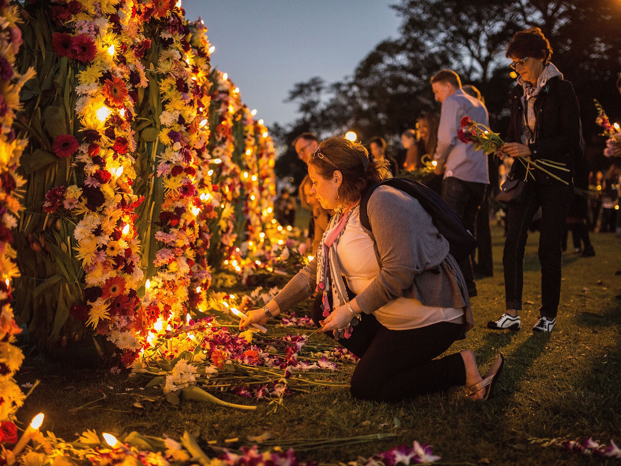 A woman places a tribute on a flower wall that reads '#keephopealive' as part of an Amnesty international vigil for the Bali 9