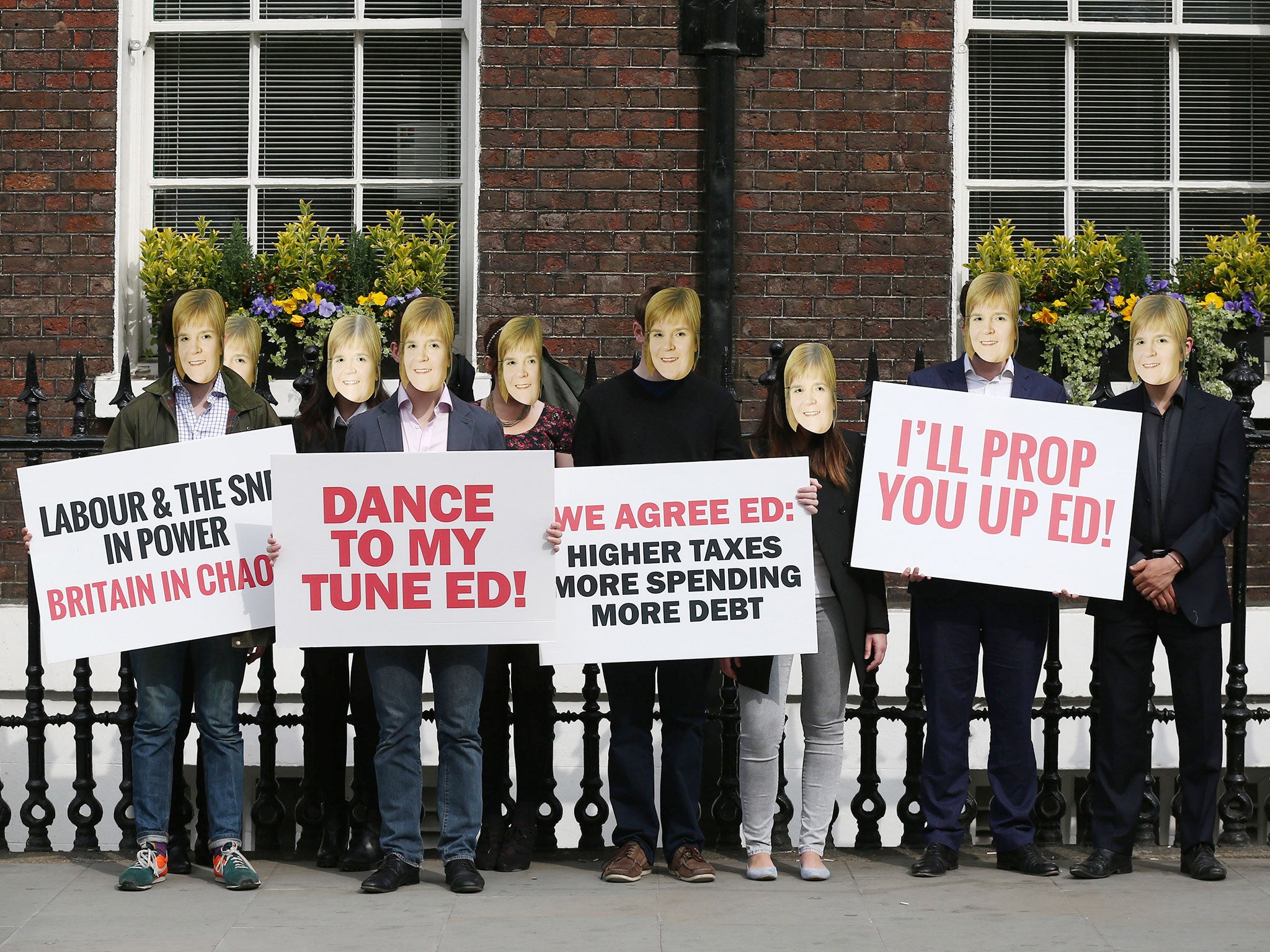 Conservative Party activists, wearing masks bearing the face of SNP leader Nicola Sturgeon, protesting ahead of a speech by Labour leader Ed Miliband at Chatham House in London (PA)