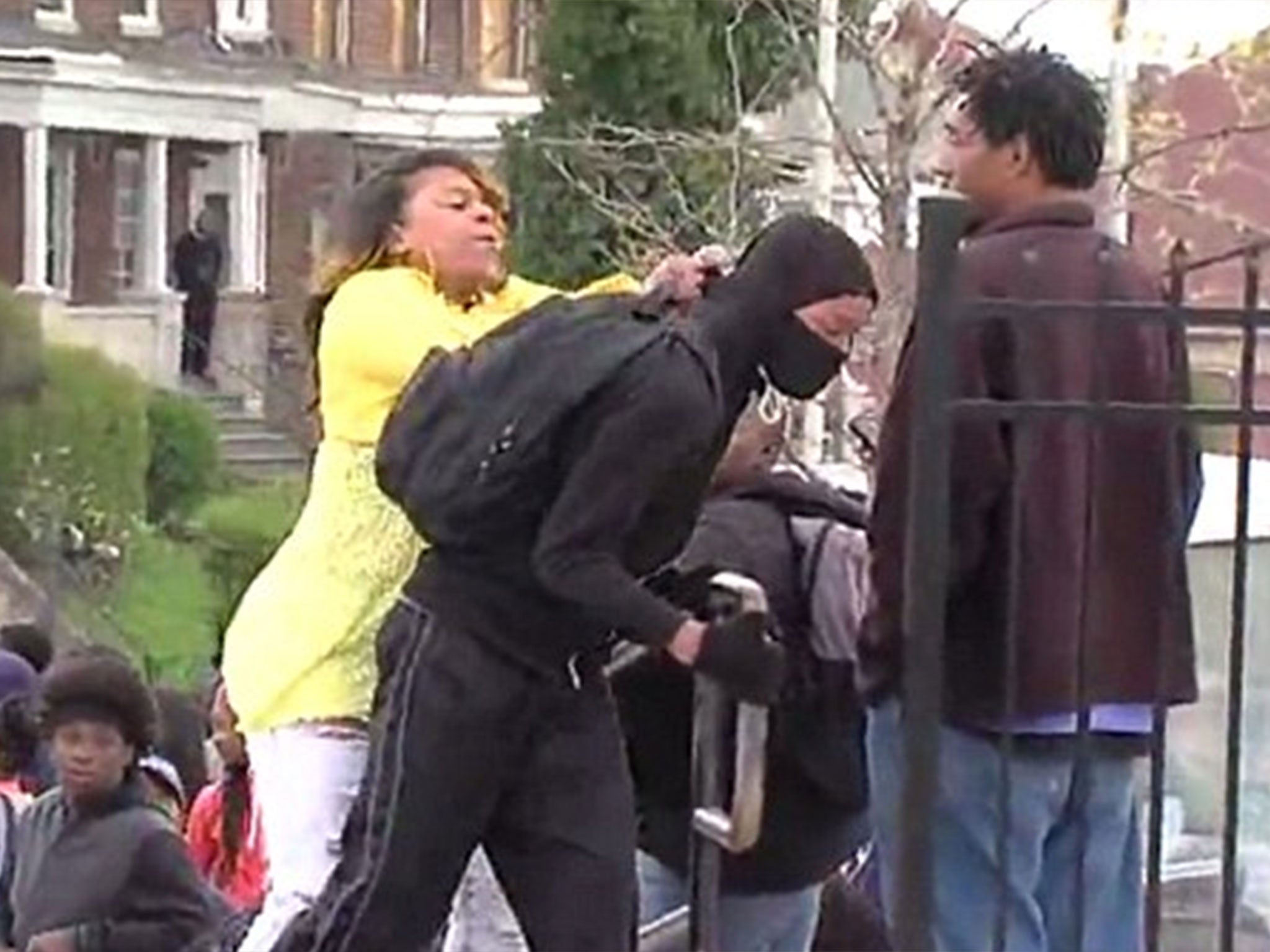 A woman reprimands a young man believed to be her son for allegedly attempting to take part in the riots