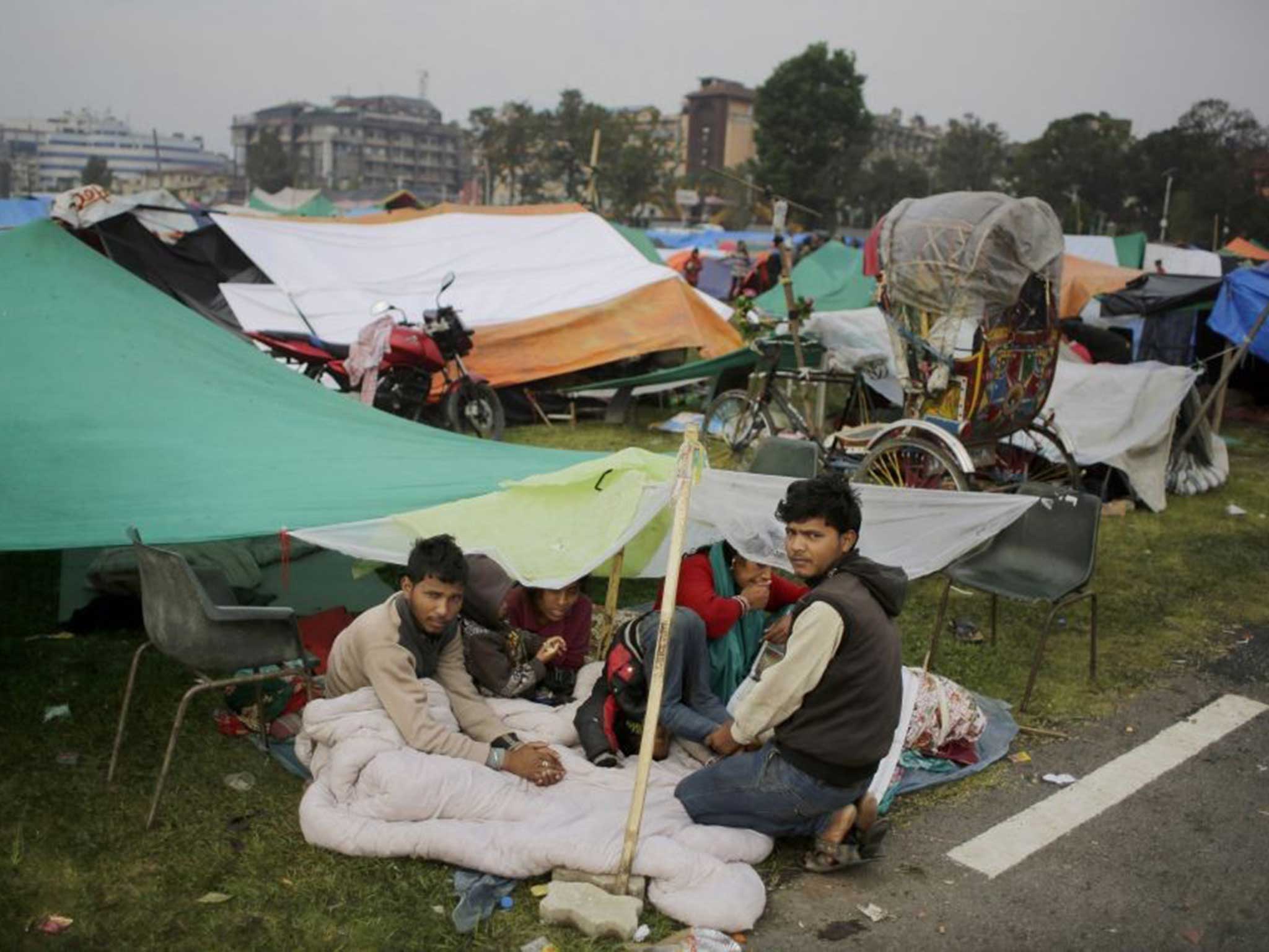 A family remain in the open for the third night following the 7.9 quake in Nepal