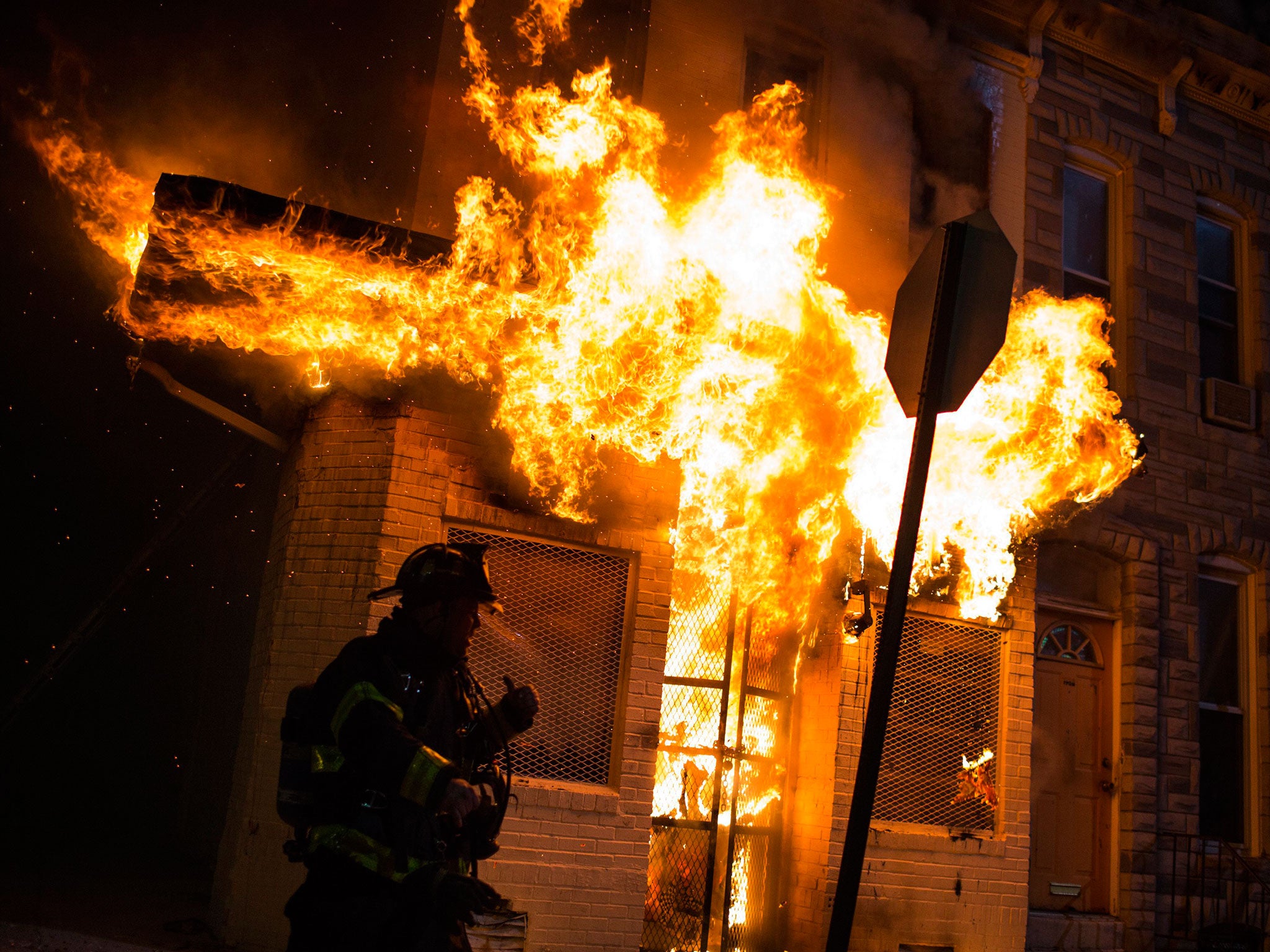 Police and firefighters respond in front of a building that caught fire as protests of the death of Freddie Gray continue in Baltimore