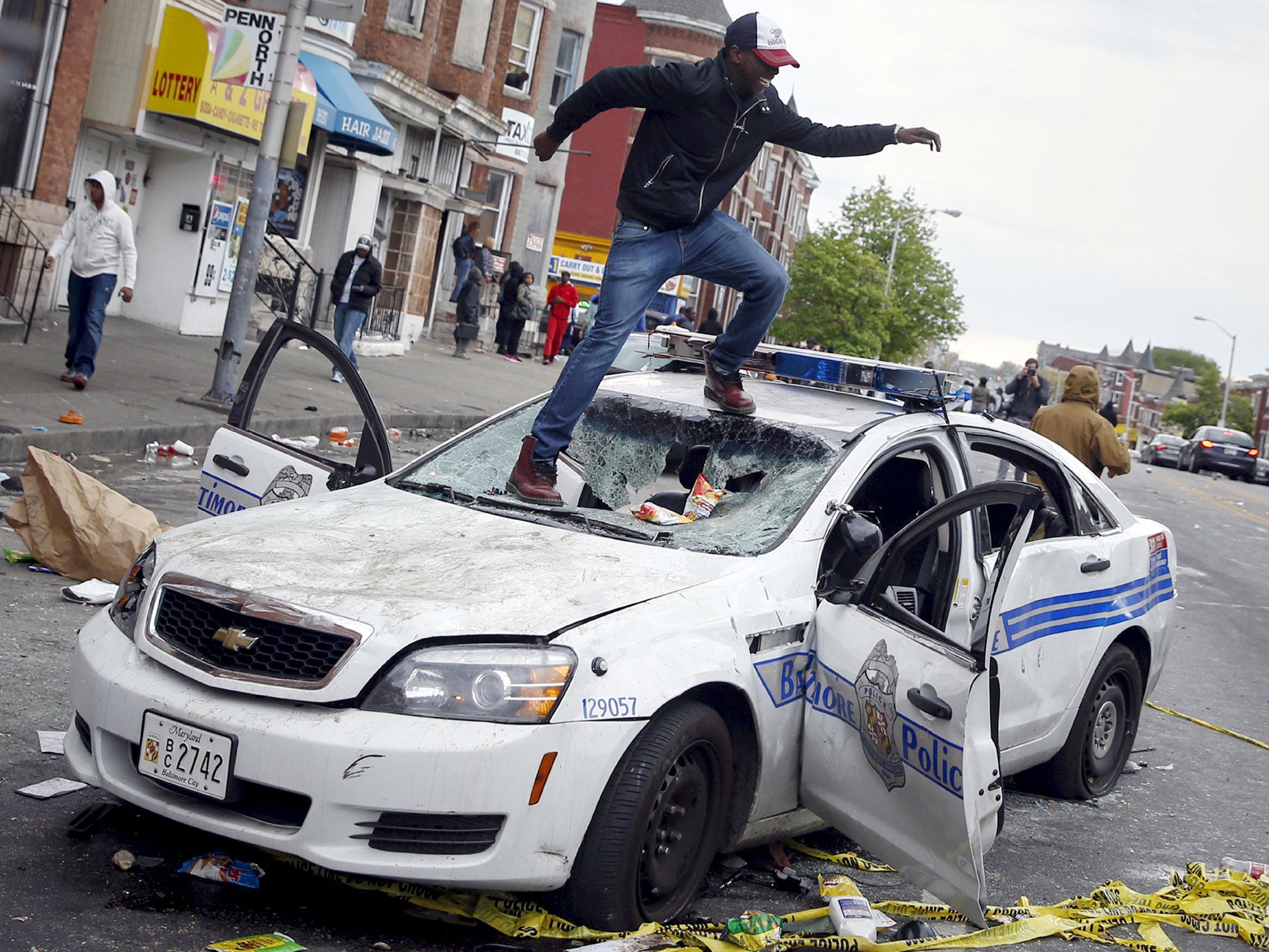 Demonstrators jump on a damaged Baltimore police department vehicle