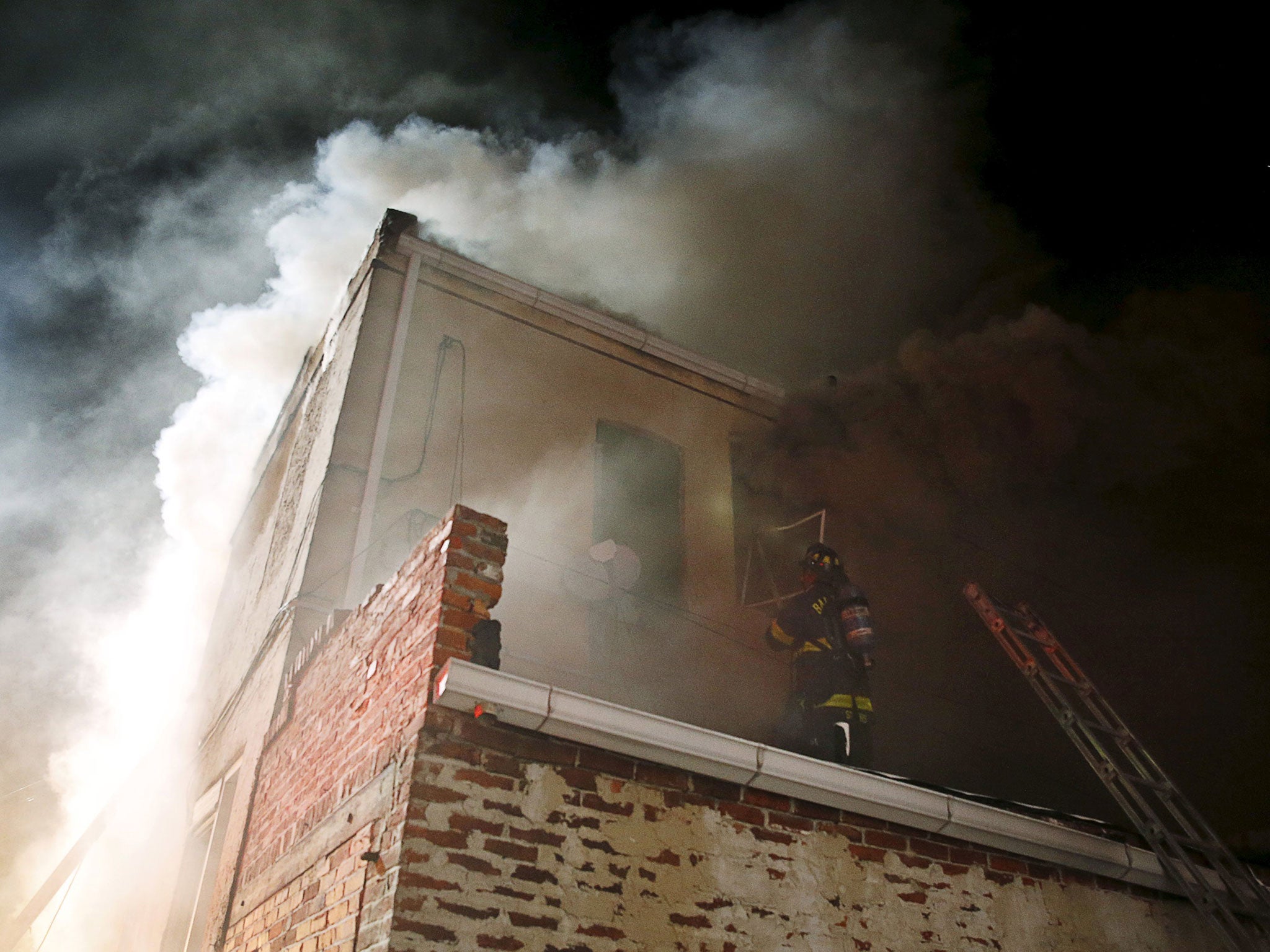 A Baltimore firefighter climbs onto a rooftop